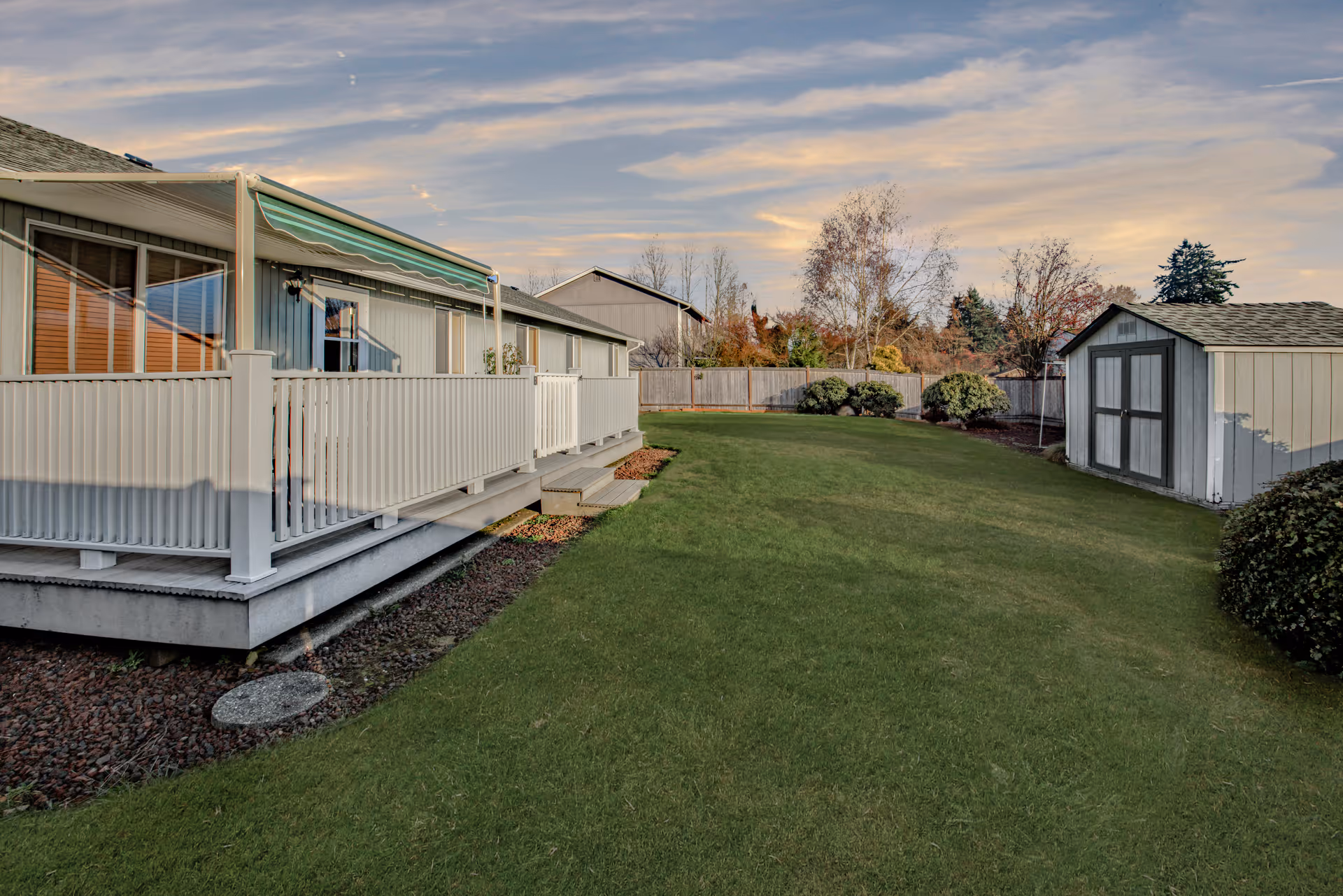 Residential outdoor yard with a long deck, white railing, and shed.