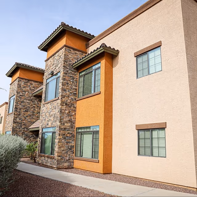 Modern senior living building exterior featuring stone columns and tinted windows.