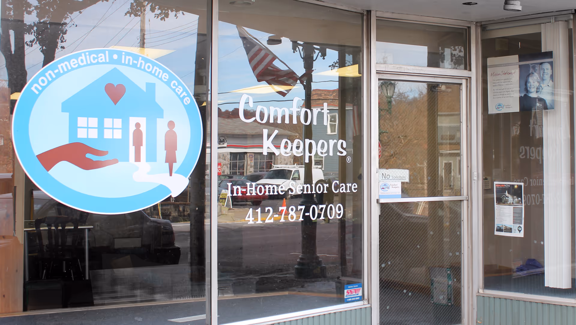 Storefront with Comfort Keepers sign and circular home-care logo on glass window