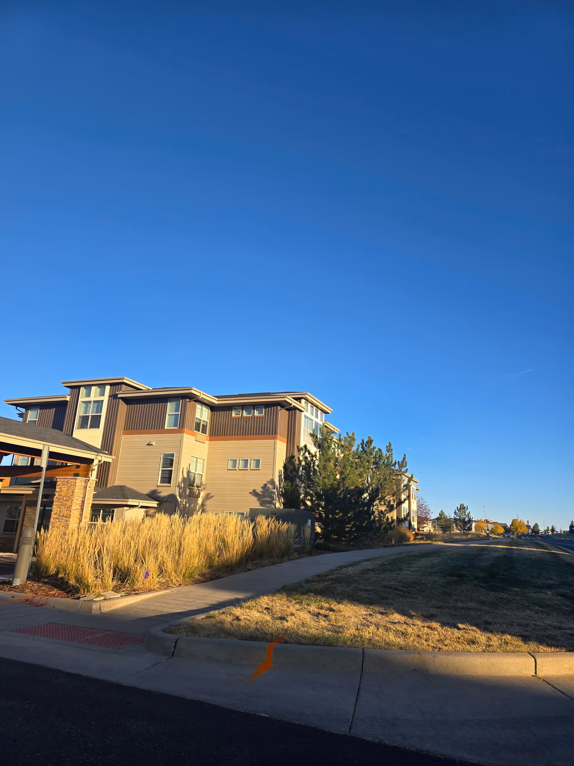 Exterior view of Bonaventure of Castle Rock senior living facility under a clear blue sky.