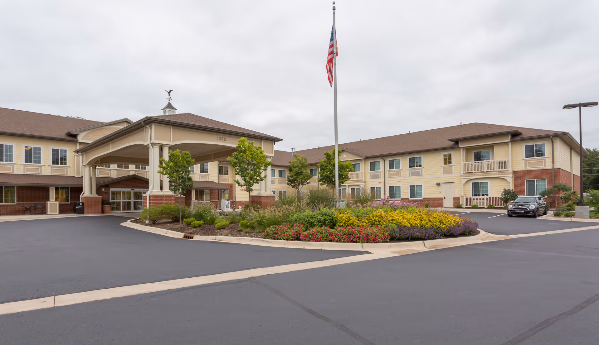 Exterior view of Three Oaks Assisted Living and Memory Care building with circular driveway and landscaping.