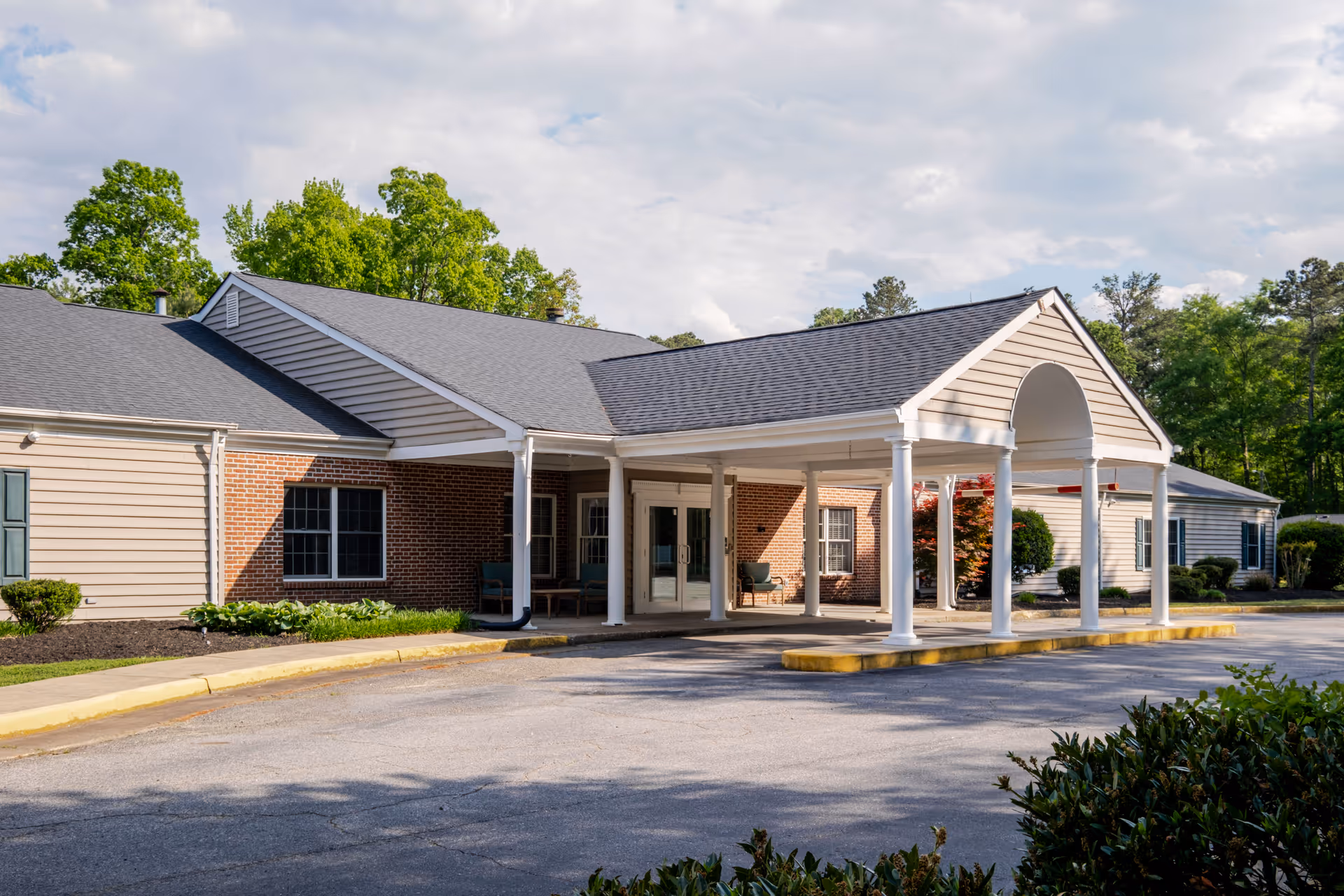 Senior living facility exterior with a covered entrance and manicured landscaping.