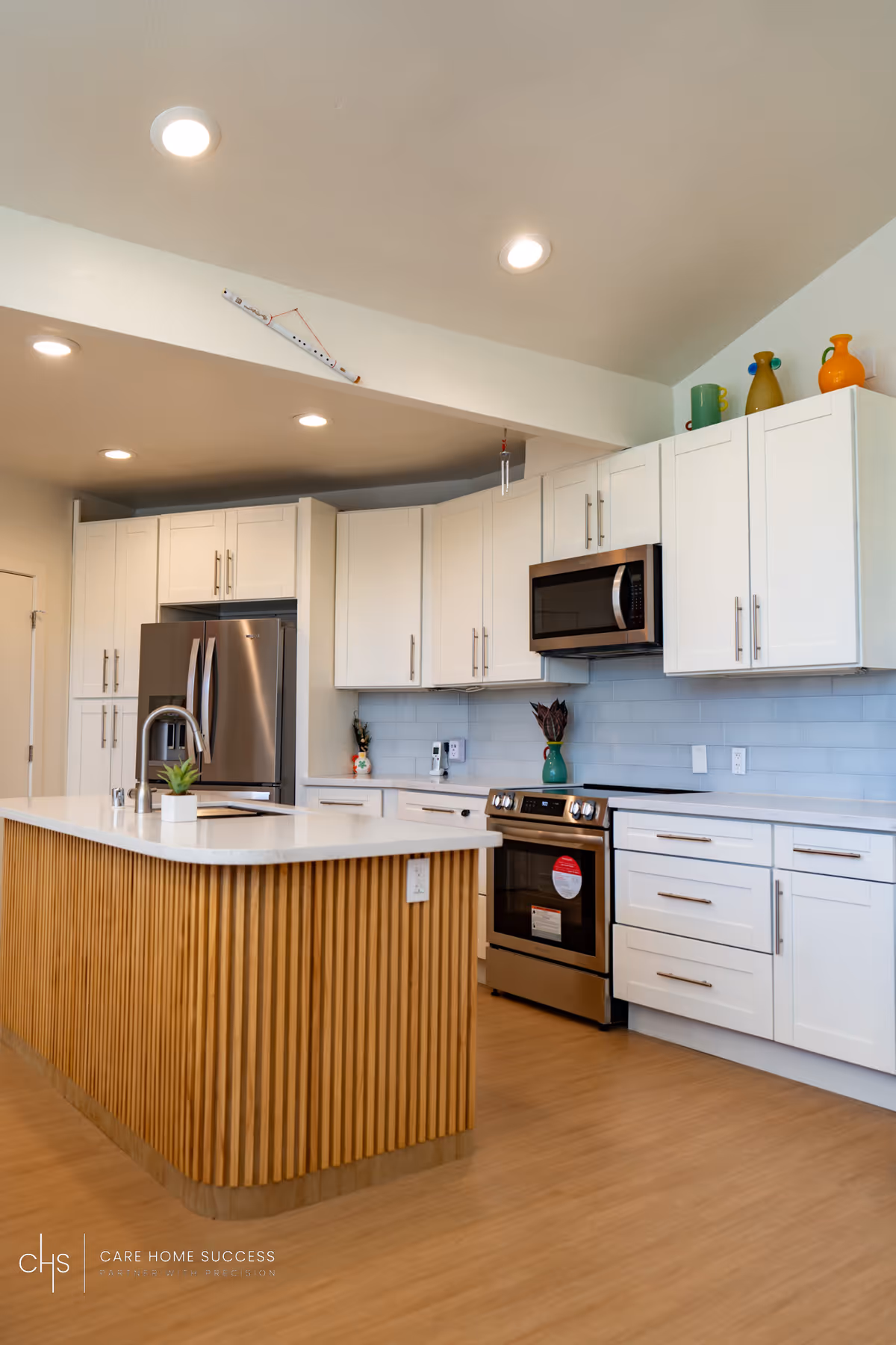 Modern white kitchen in a senior living facility with an island and stainless appliances.