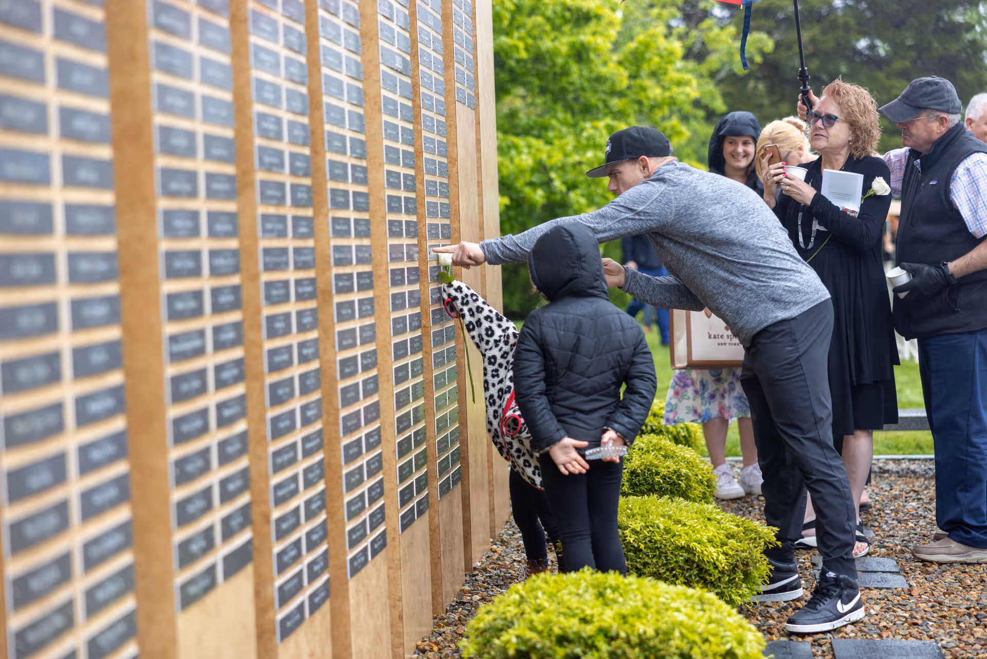 Group of people outdoors looking at a wall of name plaques.