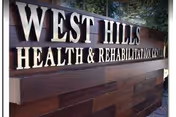 A large West Hills Health & Rehabilitation Center sign on a brick exterior wall.