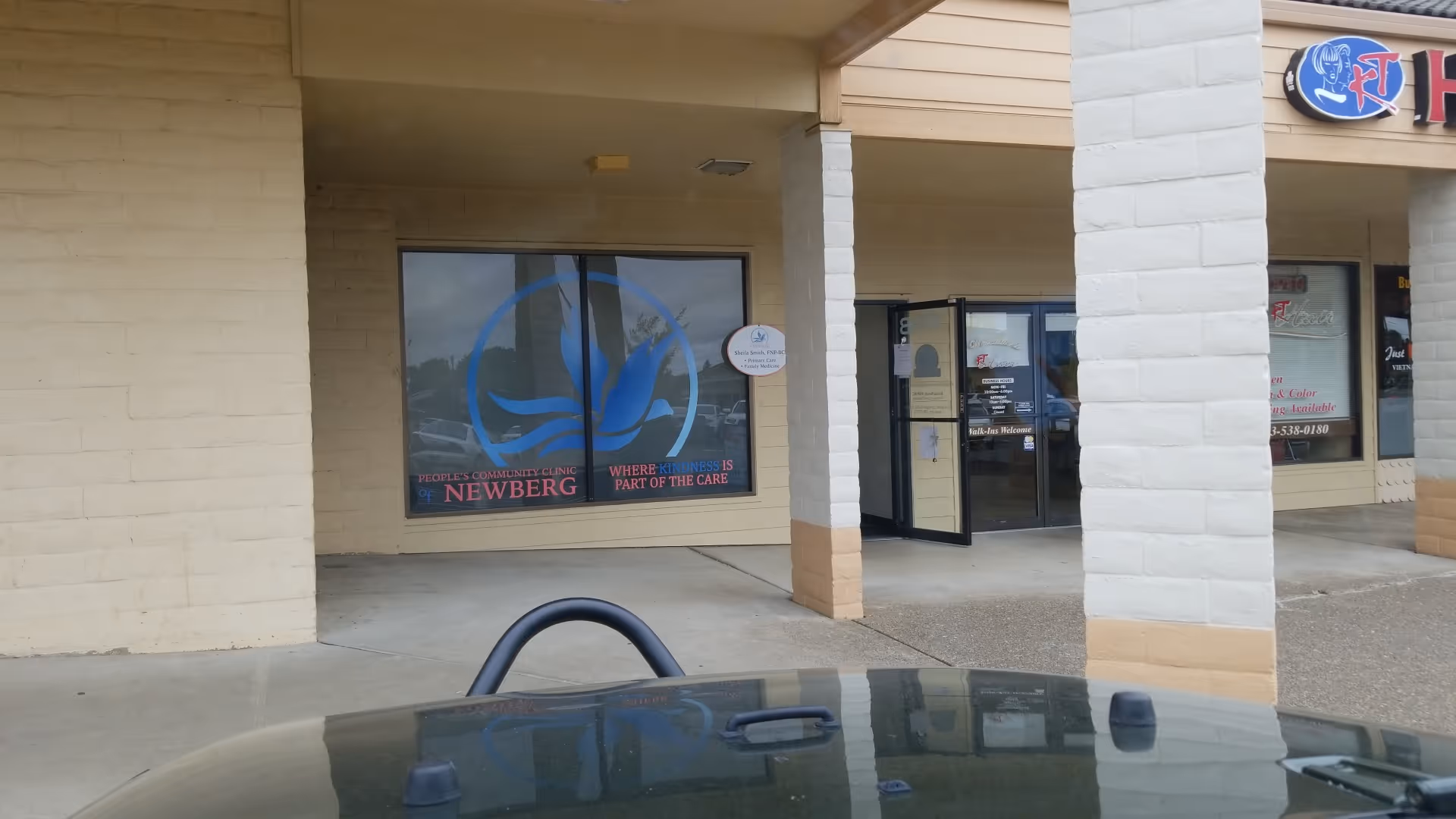 Exterior view of People's Community Clinic of Newberg storefront with glass doors and pillars.