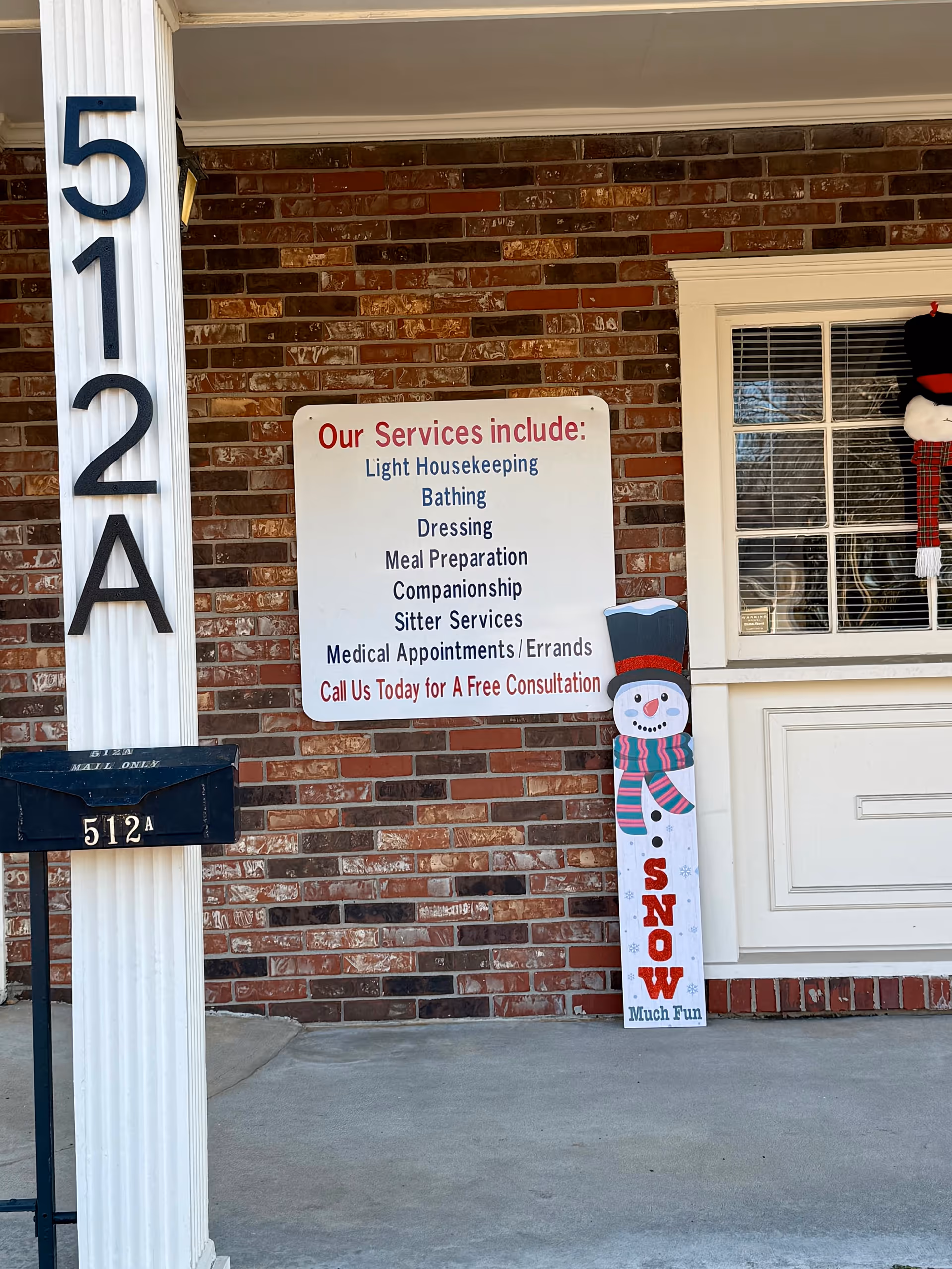 Brick building exterior showing entrance with service sign, address plaque, and a snowman decoration.