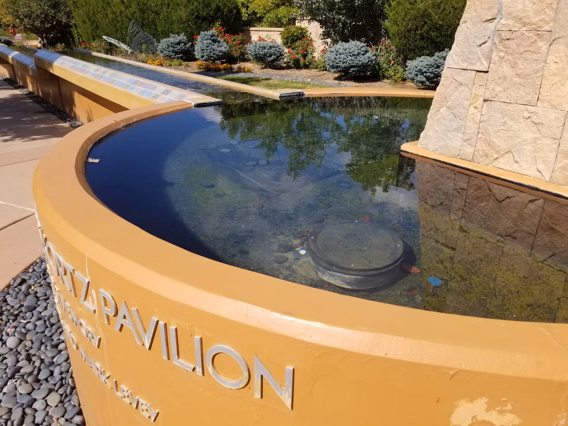 Circular outdoor fountain with stone surround and landscaped plants at Shalom Pavilion