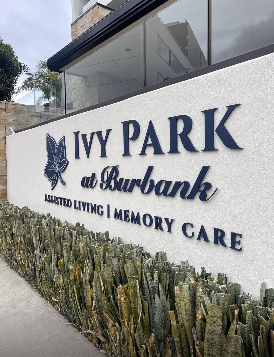 Exterior white wall sign reading Ivy Park at Burbank with surrounding landscaping.