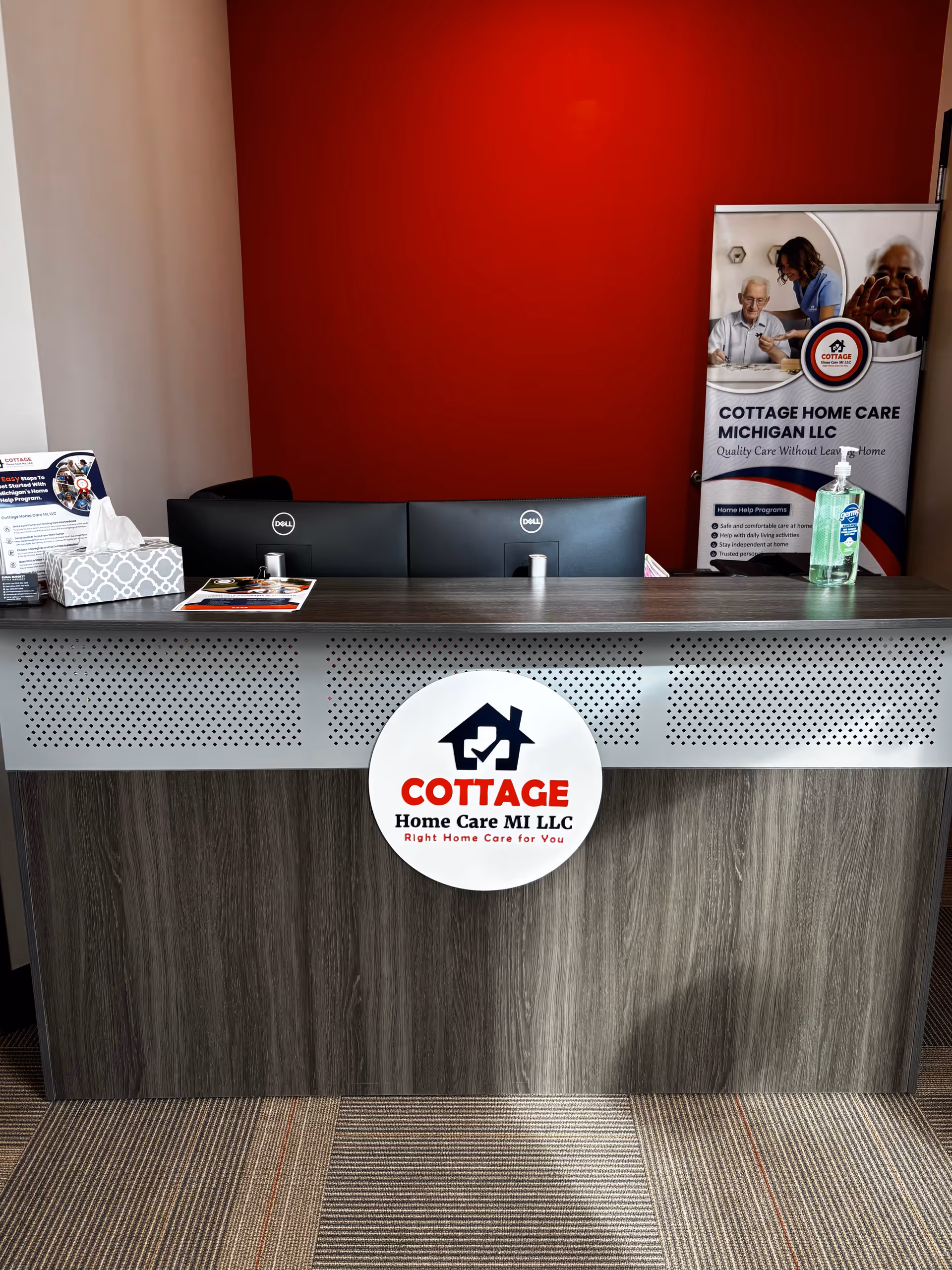Reception desk with Cottage Home Care MI LLC signage against a red wall.