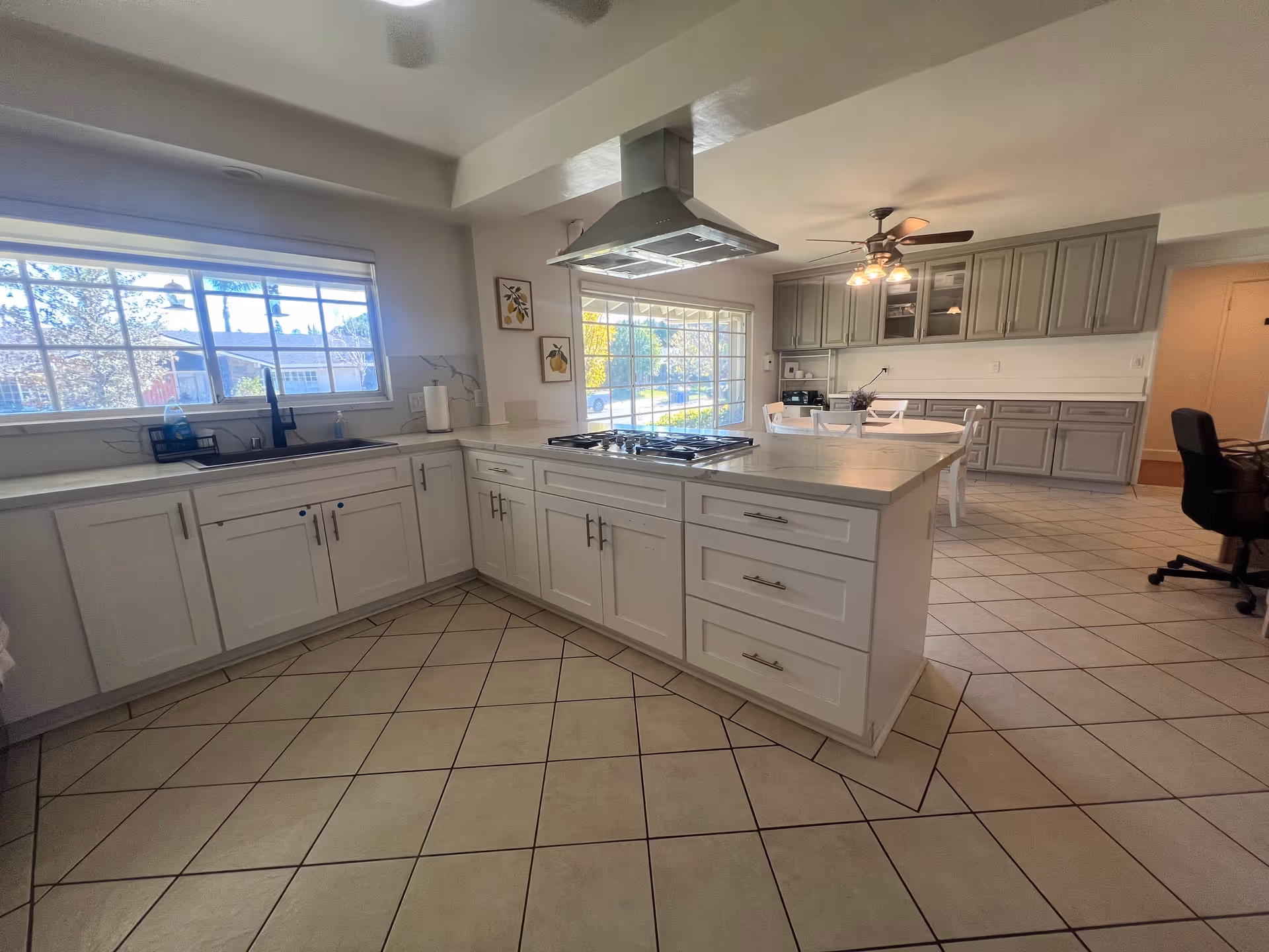 Bright modern kitchen with central island, gas range, and gray cabinetry in a senior living facility.