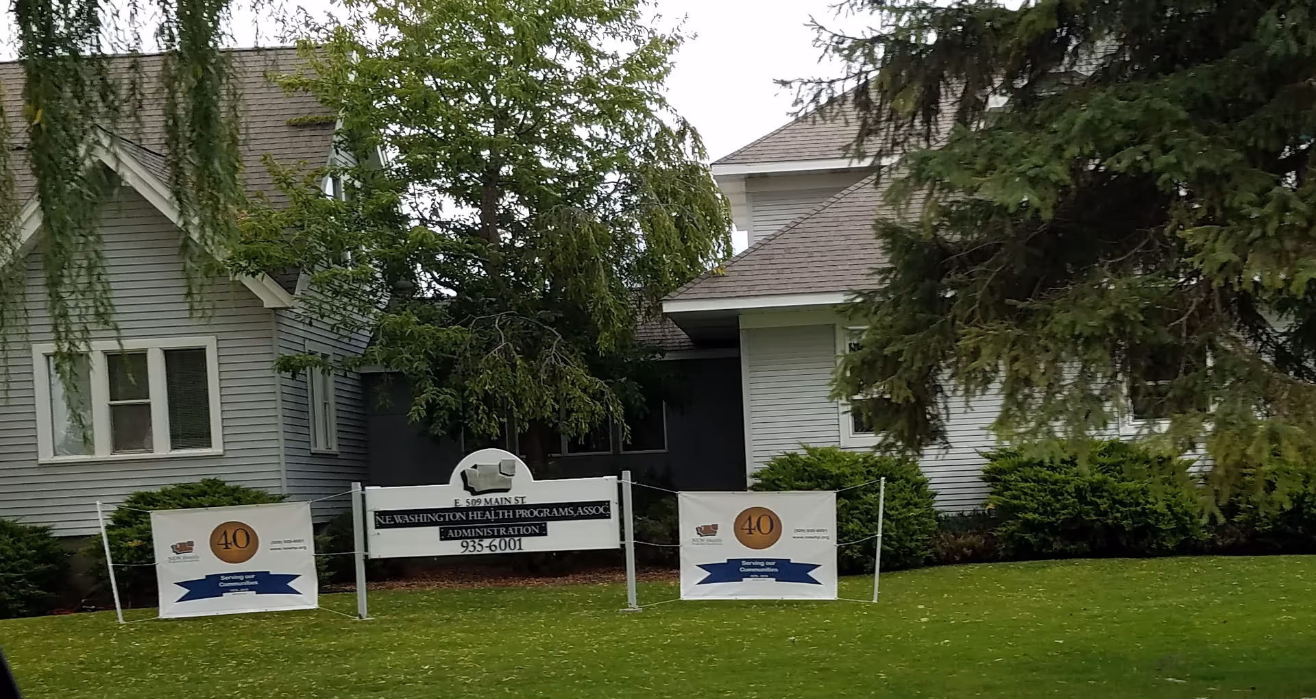 Exterior view of a New Health senior living building with banners along the lawn.