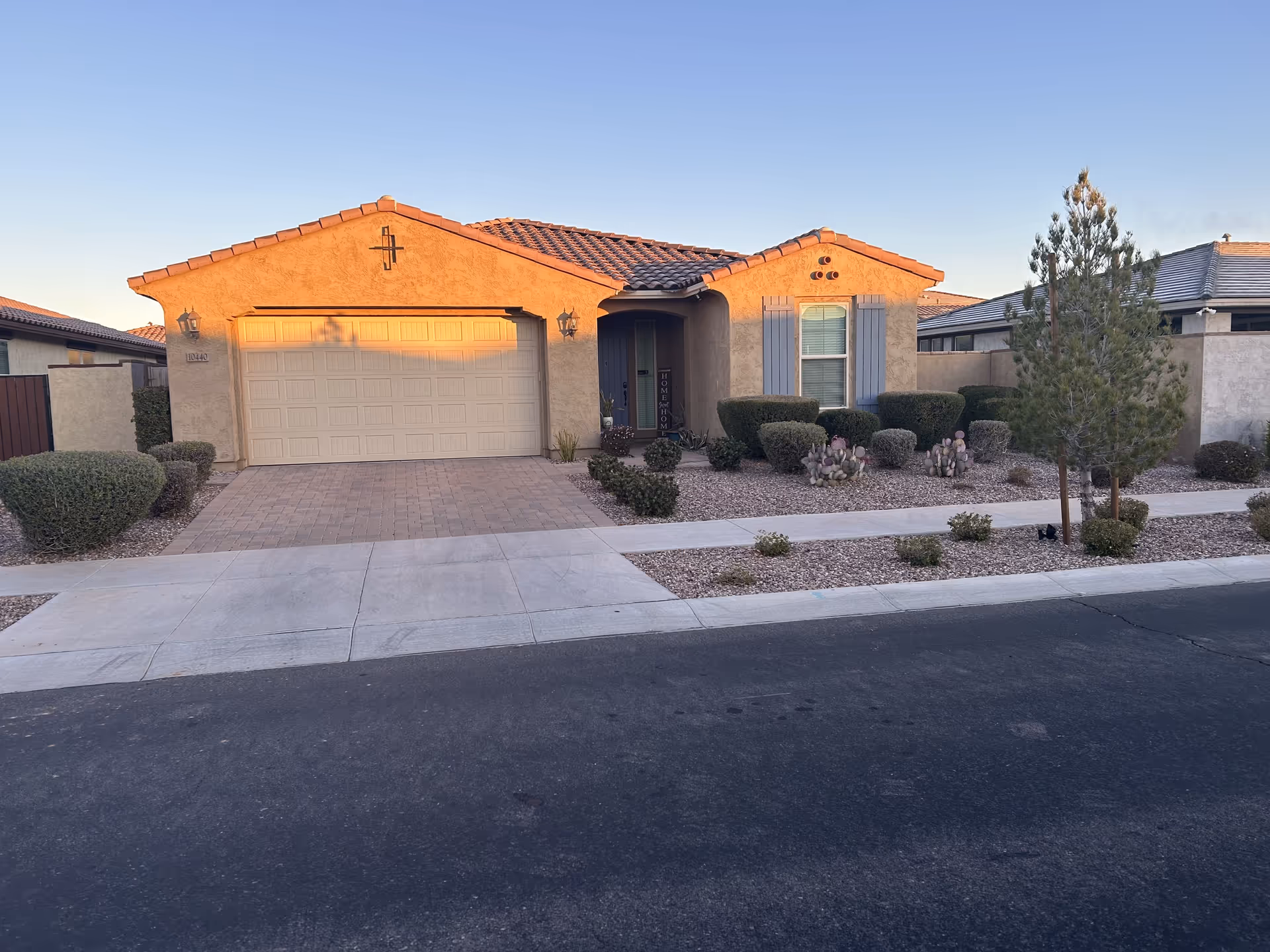 Single-story beige house with a two-car garage and desert landscaping along the front yard.