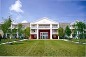 Front exterior view of a beige senior living building with a green lawn and trees.
