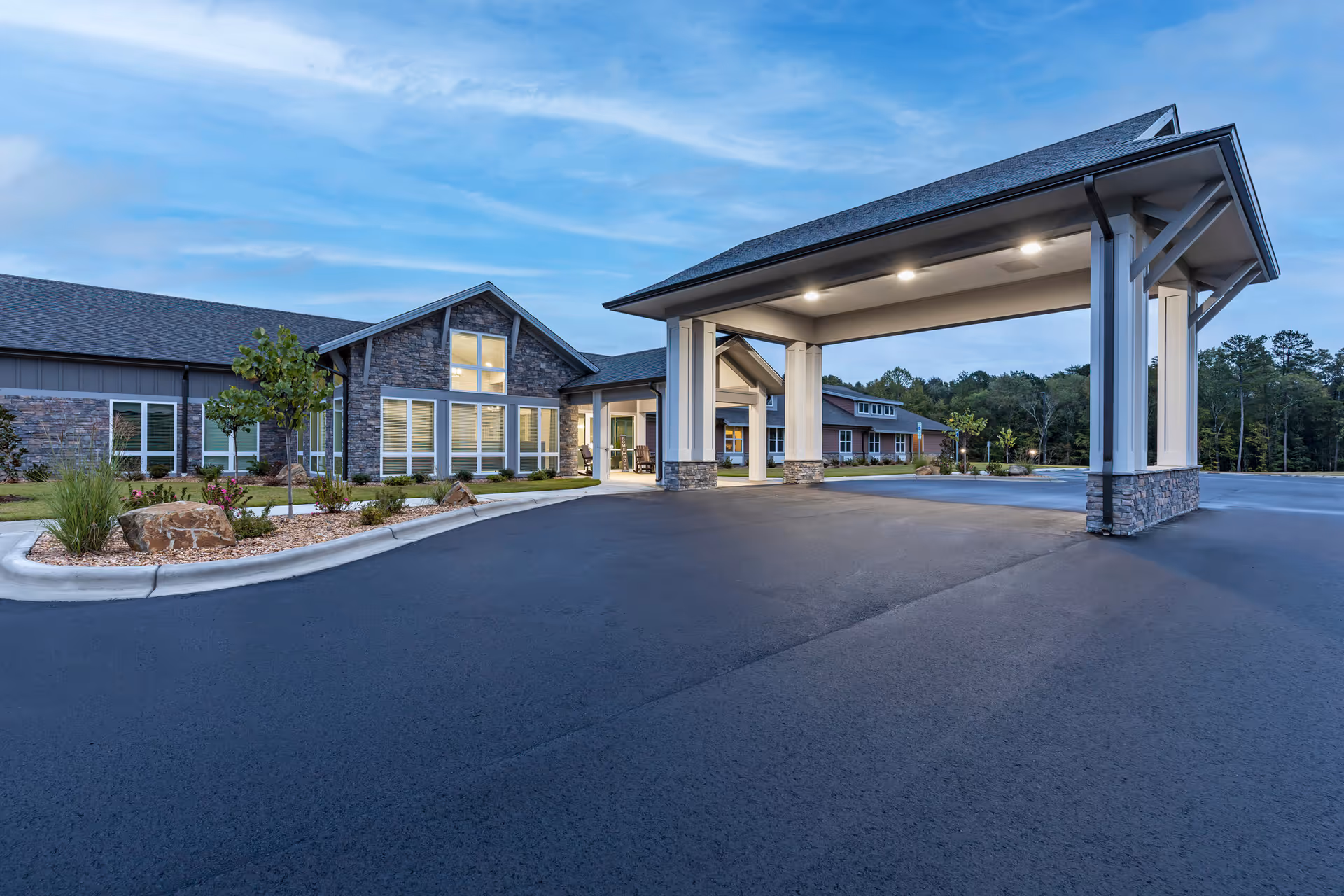 Exterior view of The Drake senior living facility with a covered entrance and large driveway.