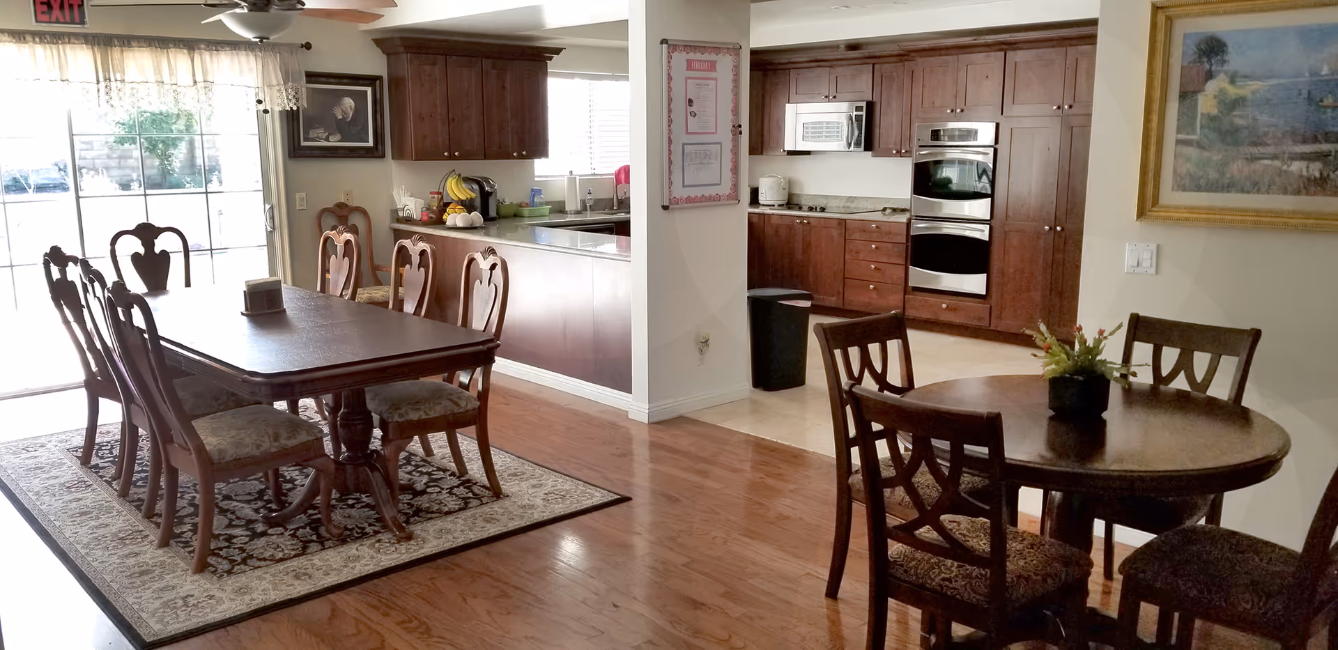 Open dining area with wooden tables, chairs, and a kitchen in the background.