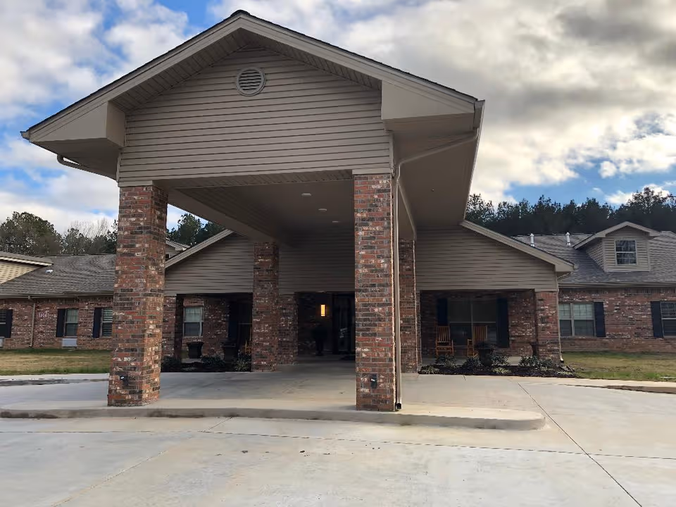 Front entrance of Landmark of Collins senior living facility with brick columns and covered canopy.