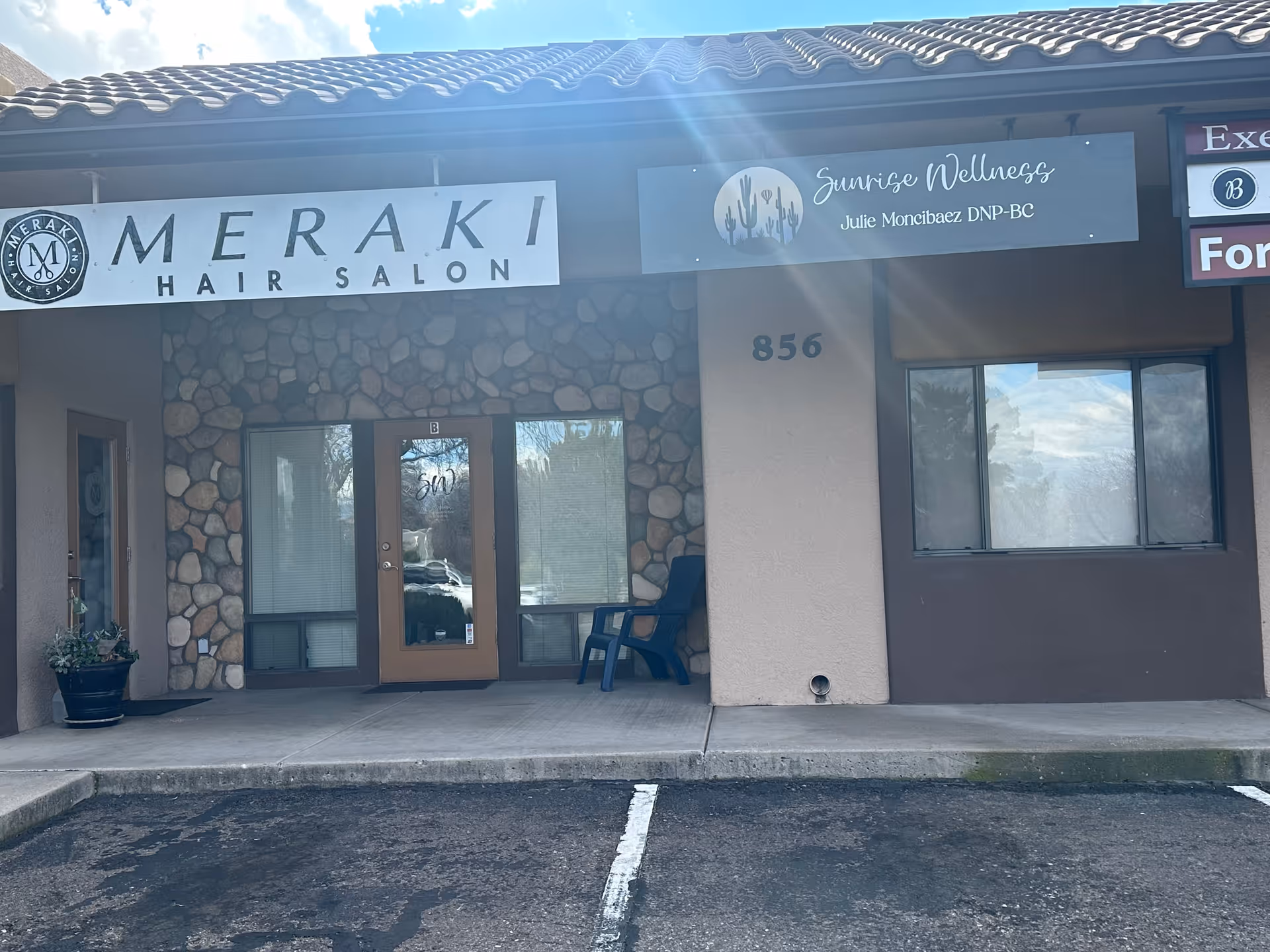 Exterior storefront with Sunrise Wellness signage beside Meraki Hair Salon on stone facade.