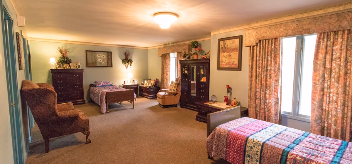 A cozy, spacious shared bedroom in Haven Adult Foster Care with multiple beds and furnishings.