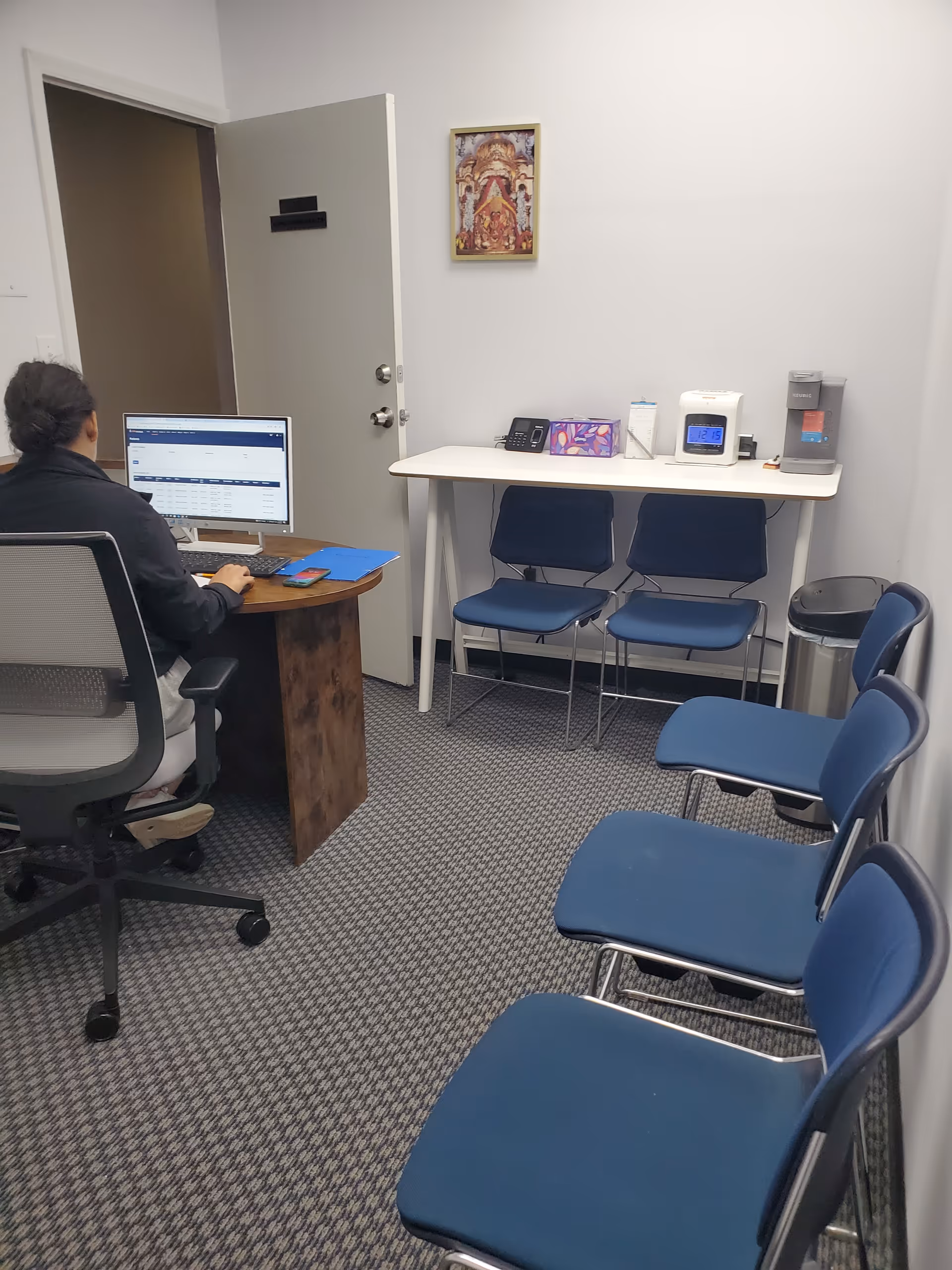 A small office in a senior facility with a person at a desk and waiting chairs.