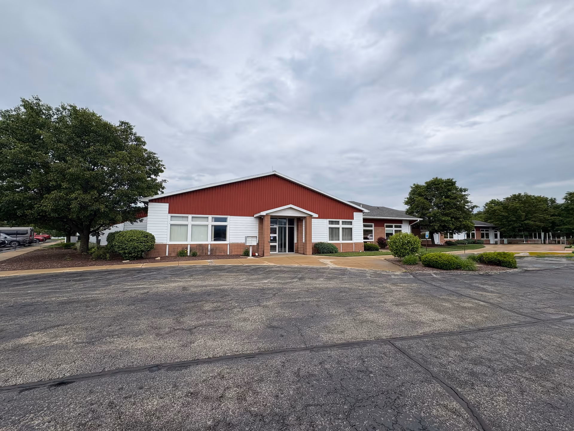 Exterior view of BAYADA Habilitation facility with a red gable roof and parking lot.