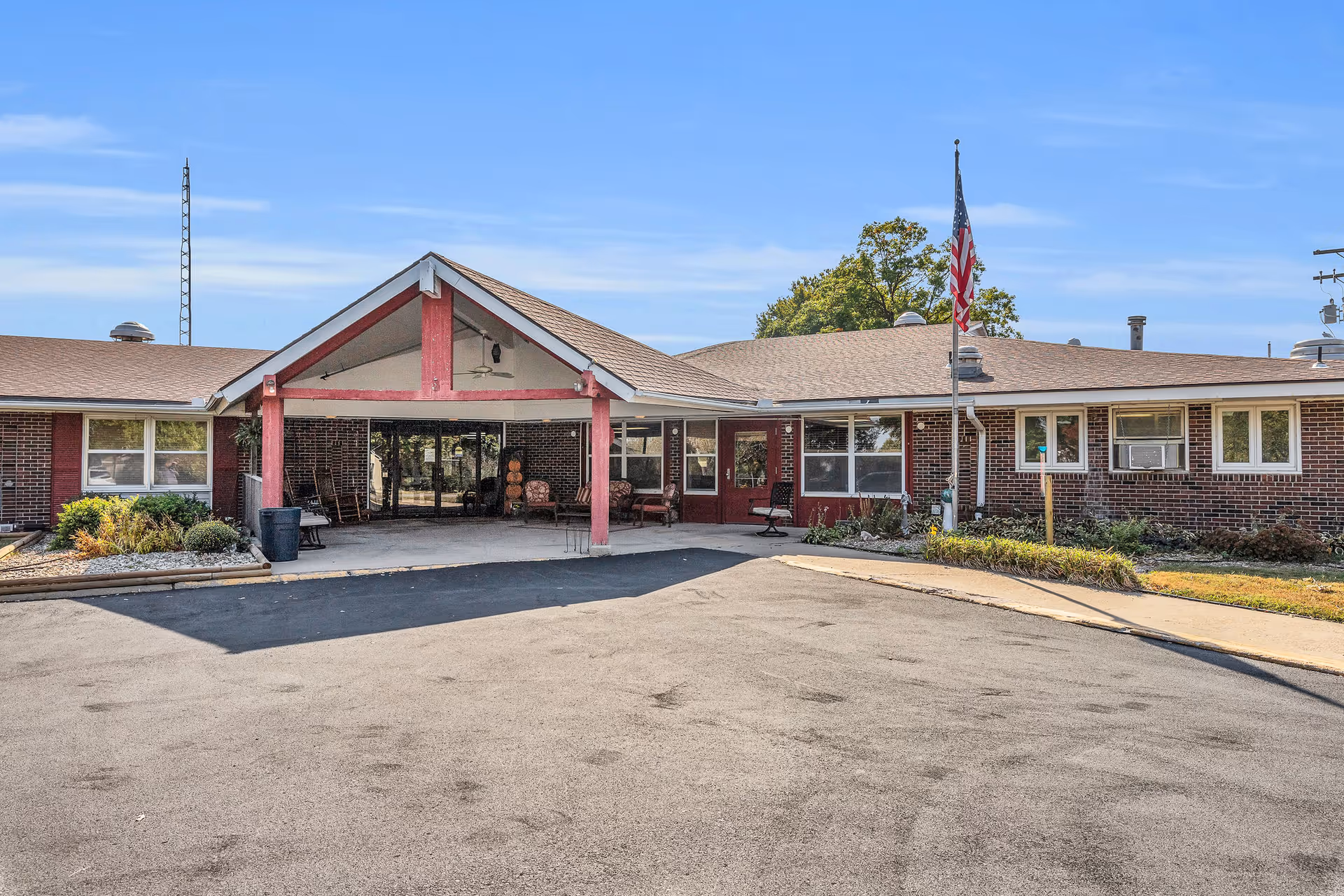 Front view of a brick senior living facility with a covered entrance and flagpole.