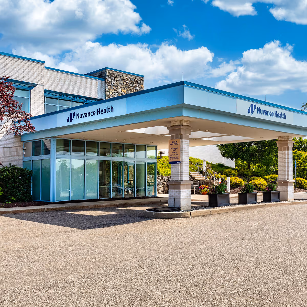 Nuvance Health entrance with glass doors, blue canopy, and landscaped walkway.