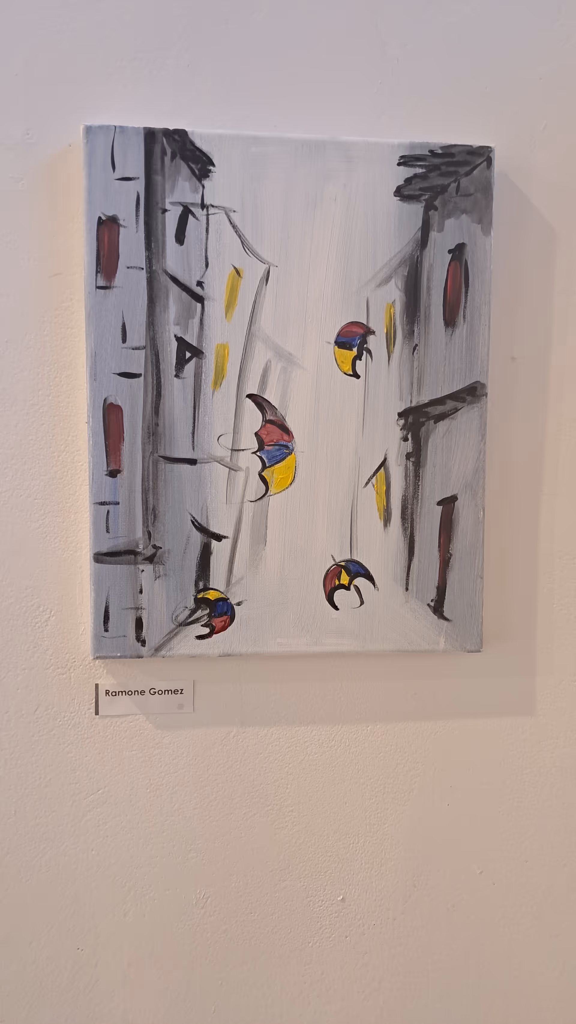 An abstract painting of colorful umbrellas on a gray city street displayed on a white wall.