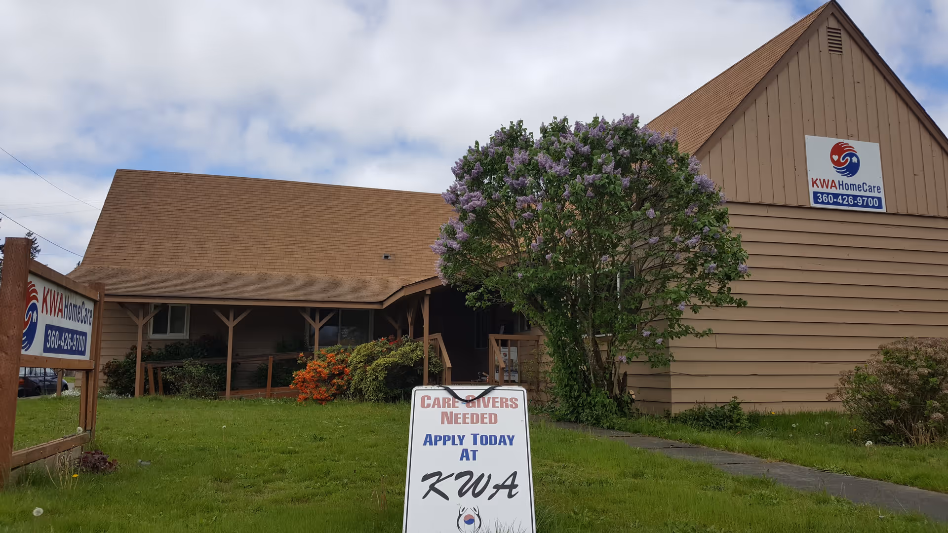 Exterior view of KWA HomeCare facility with lawn and signs.