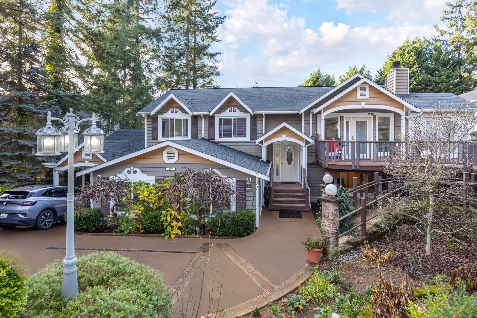 Two-story senior living home with front entrance, driveway, garden, and a parked car.