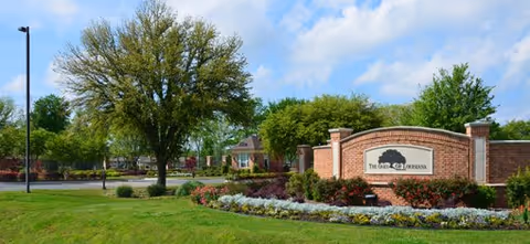 Front entrance of The Oaks of Louisiana with brick signage and trees.