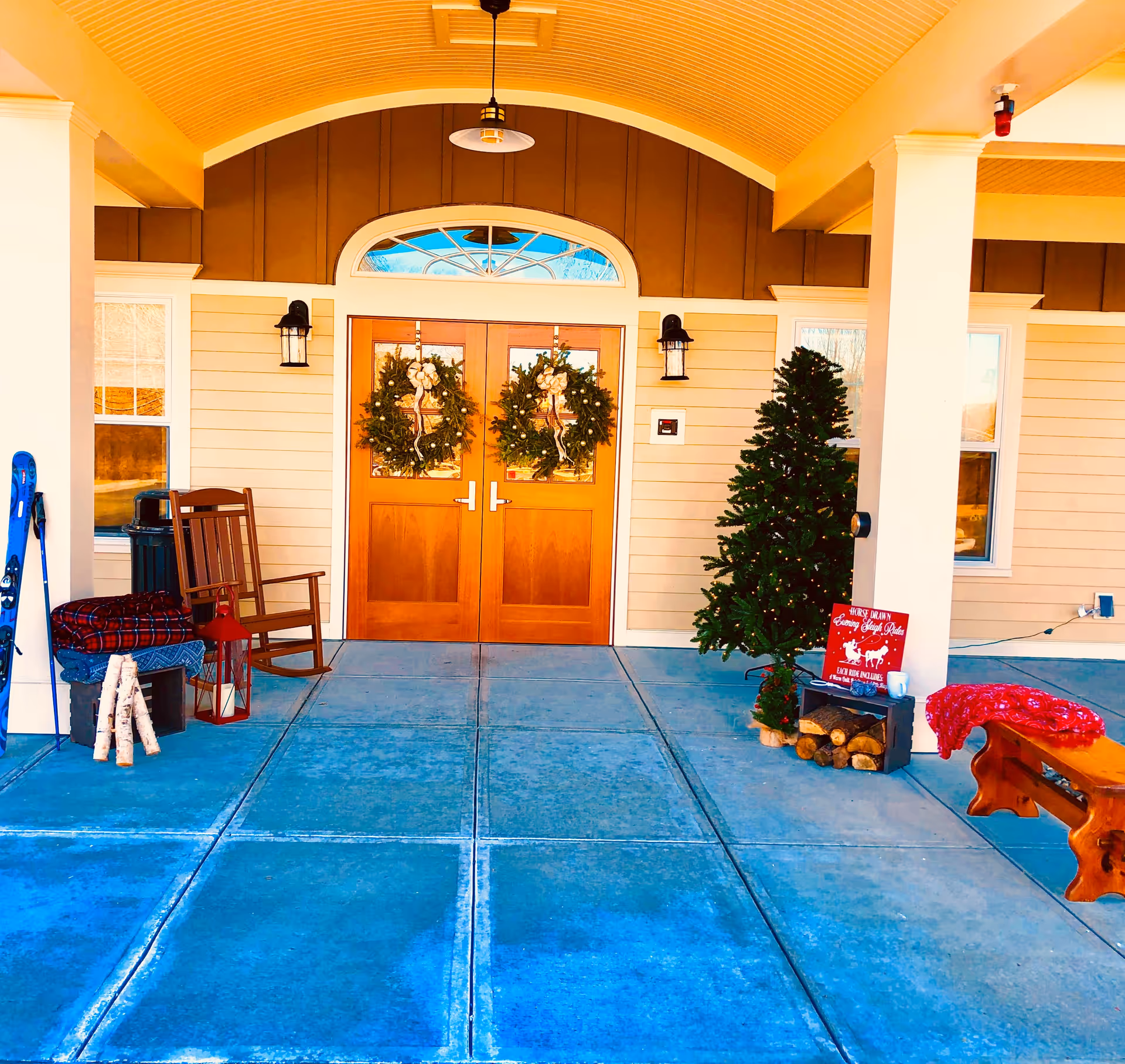 Front entrance with wreaths on double wooden doors and holiday decorations.