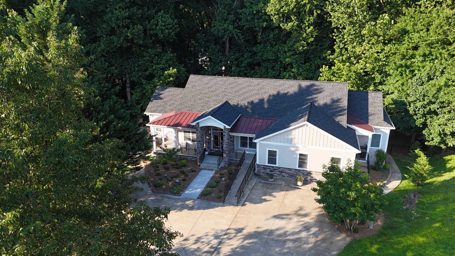A single-story senior living facility exterior with a driveway, entrance, and surrounding trees.