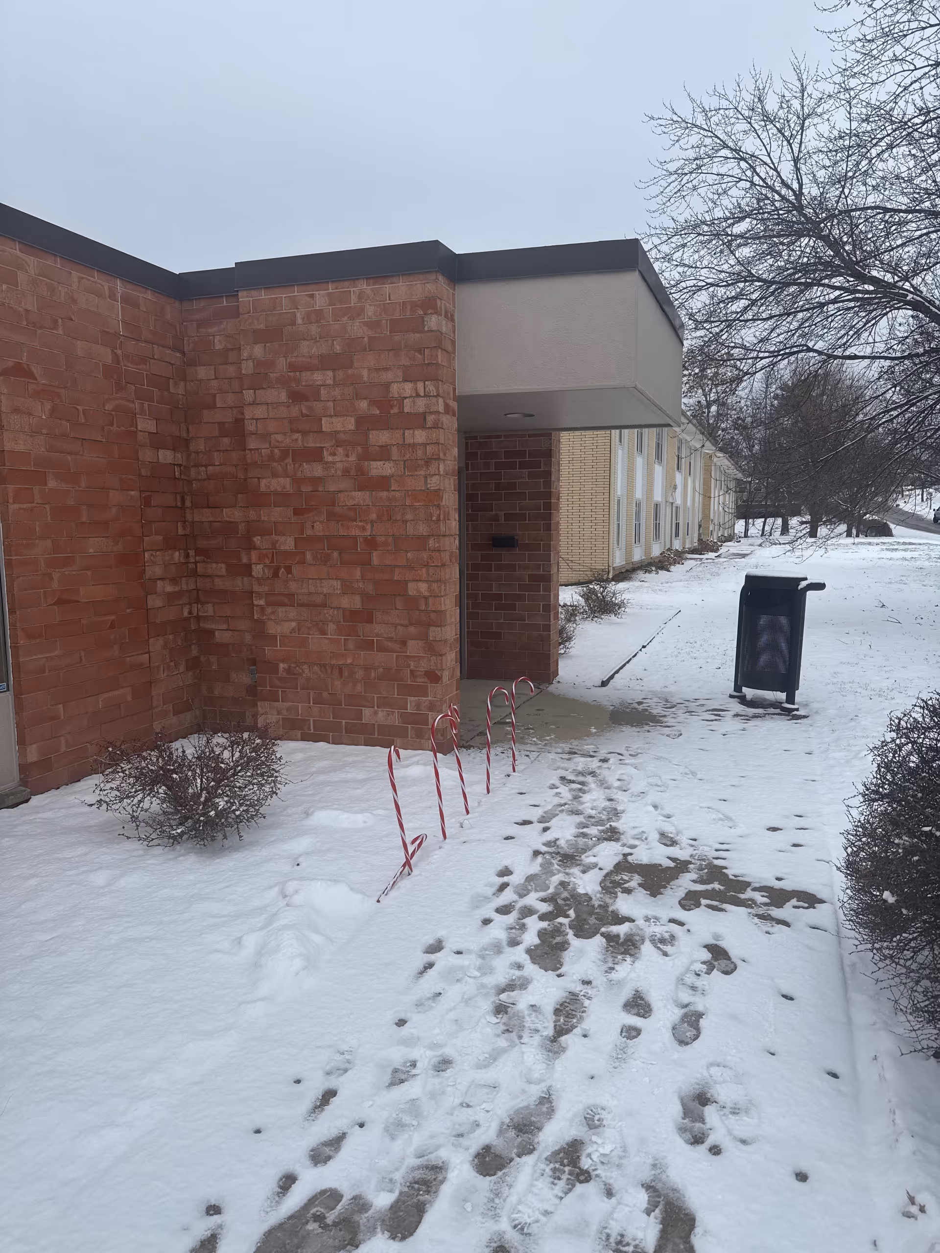 Snow-covered exterior of Sunlight Senior Care- Des Moines with brick walls and entrance.