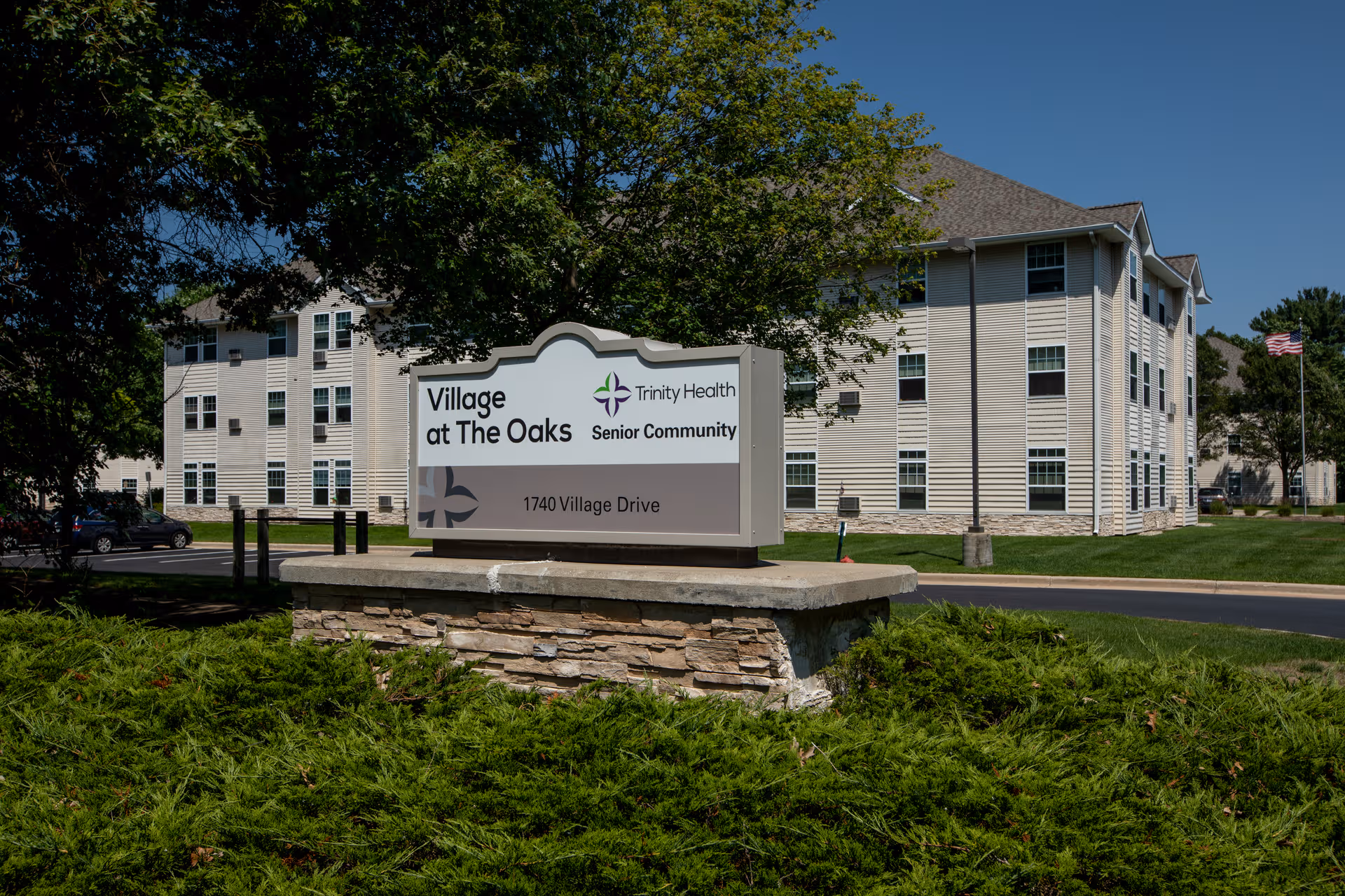 Exterior view of Village at The Oaks senior living facility with sign and front building