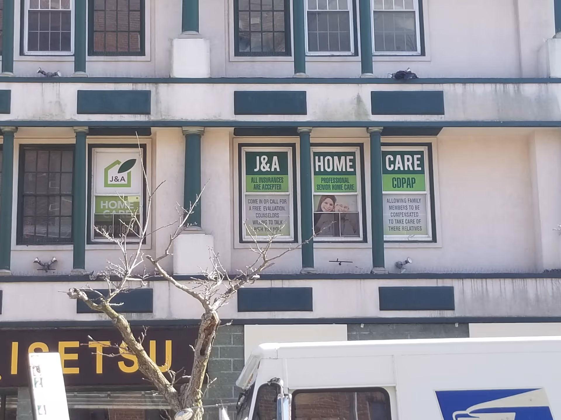 Facade of a multi-story building with J&A Home Care window advertisements.