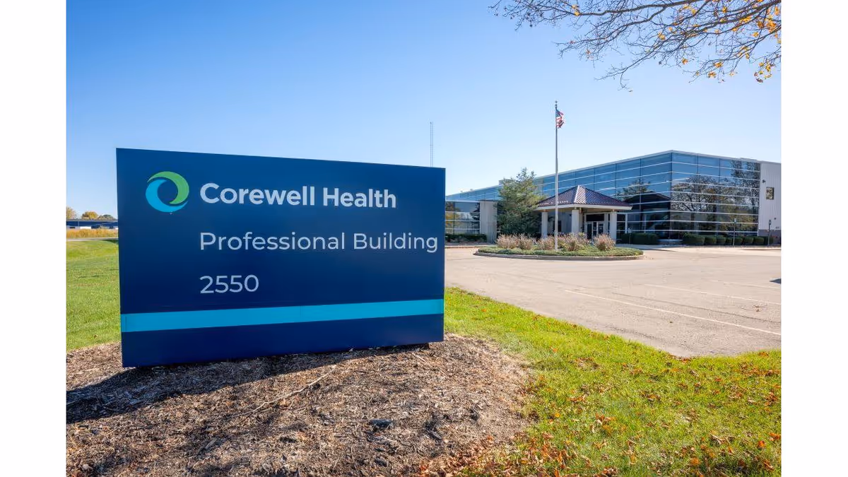 Blue Corewell Health sign in foreground with a glass-front professional building behind.