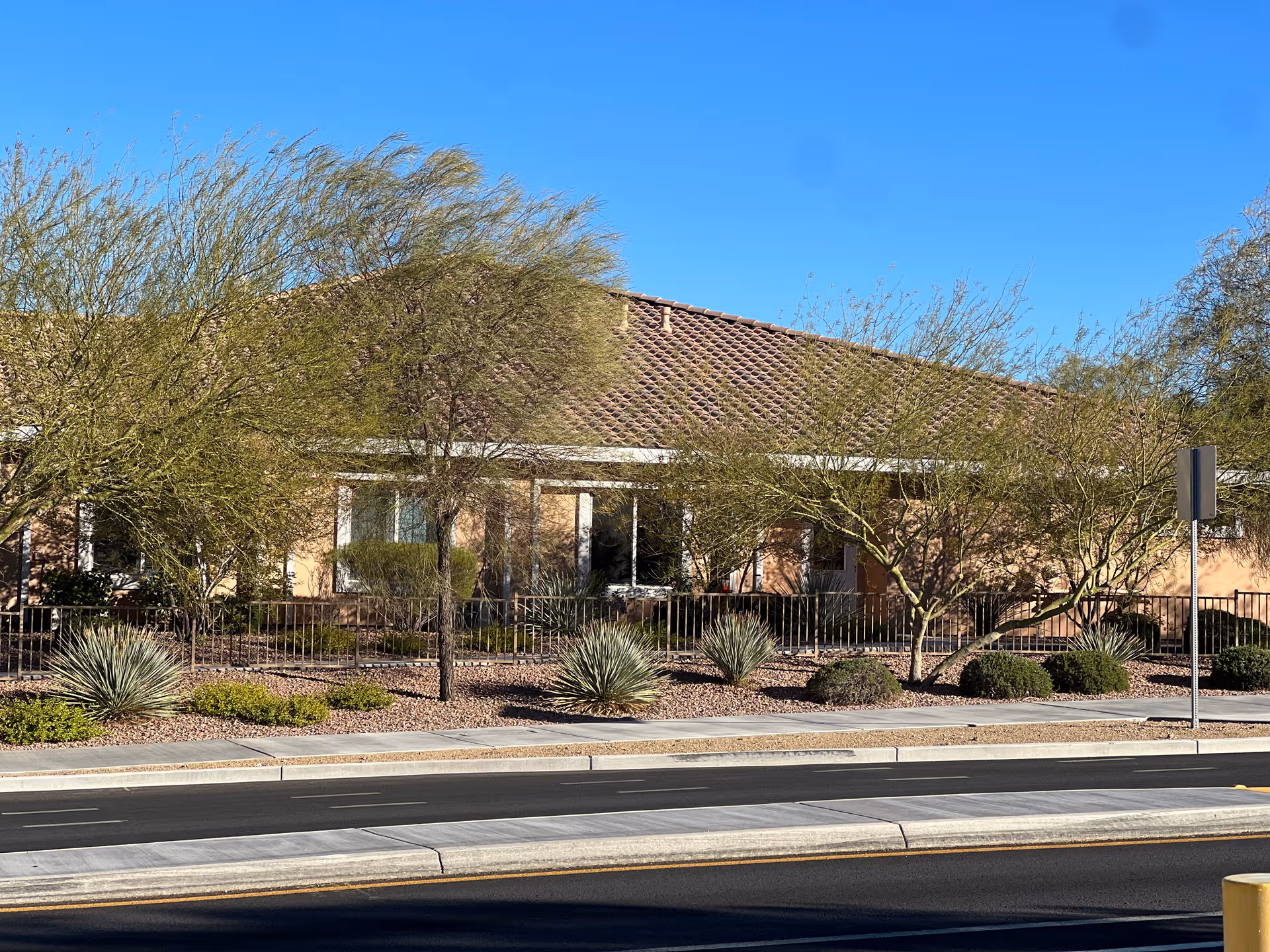 Single-story senior living facility exterior with desert landscaping and a street in front.