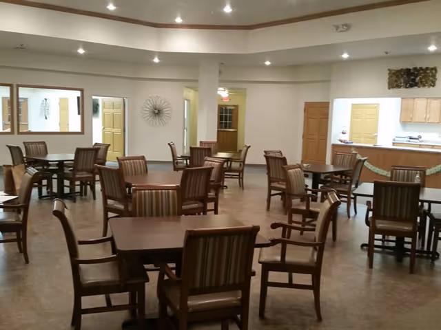 Spacious senior living dining room with multiple wooden tables and chairs.