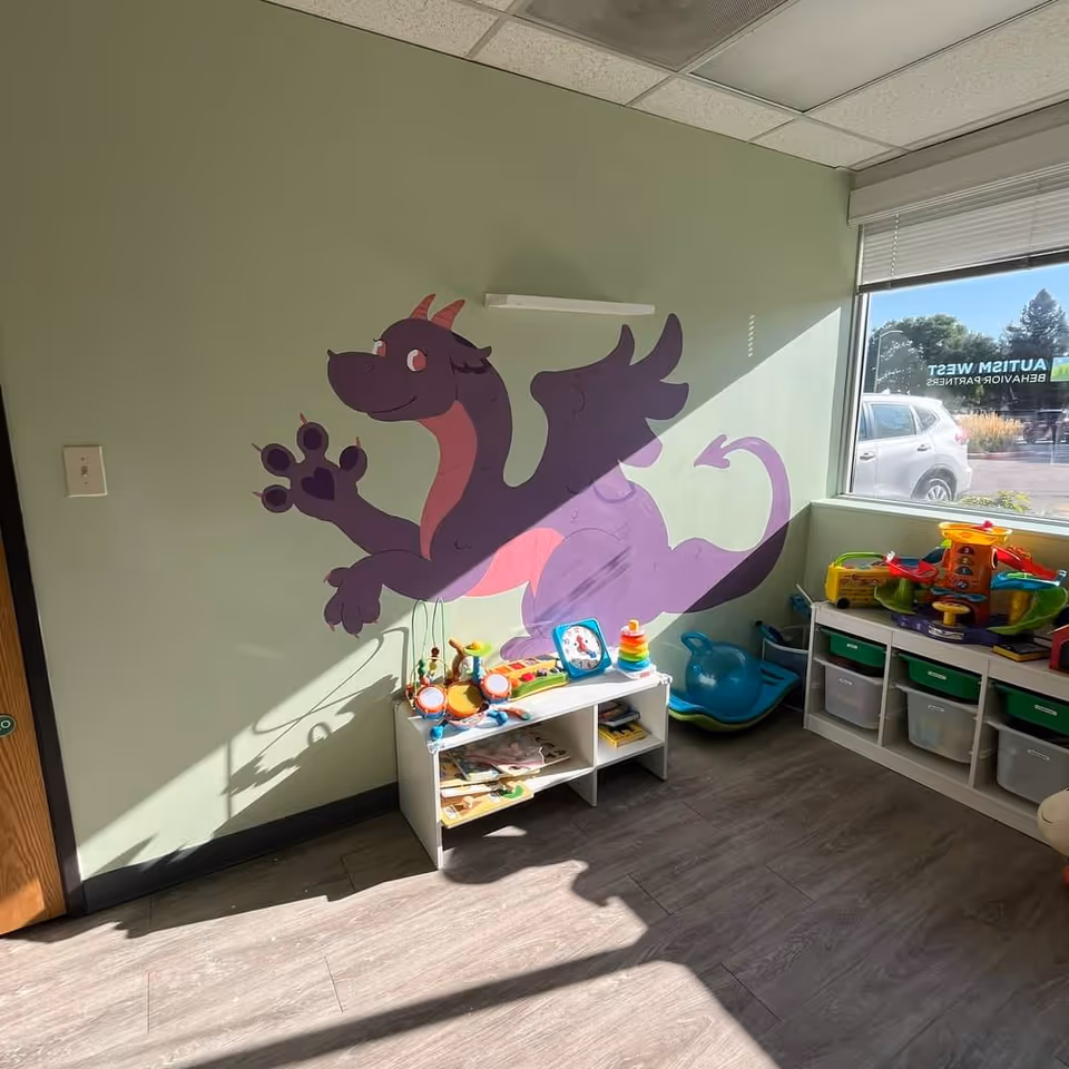 Play area in an interior room featuring a purple dragon mural and toy shelves.