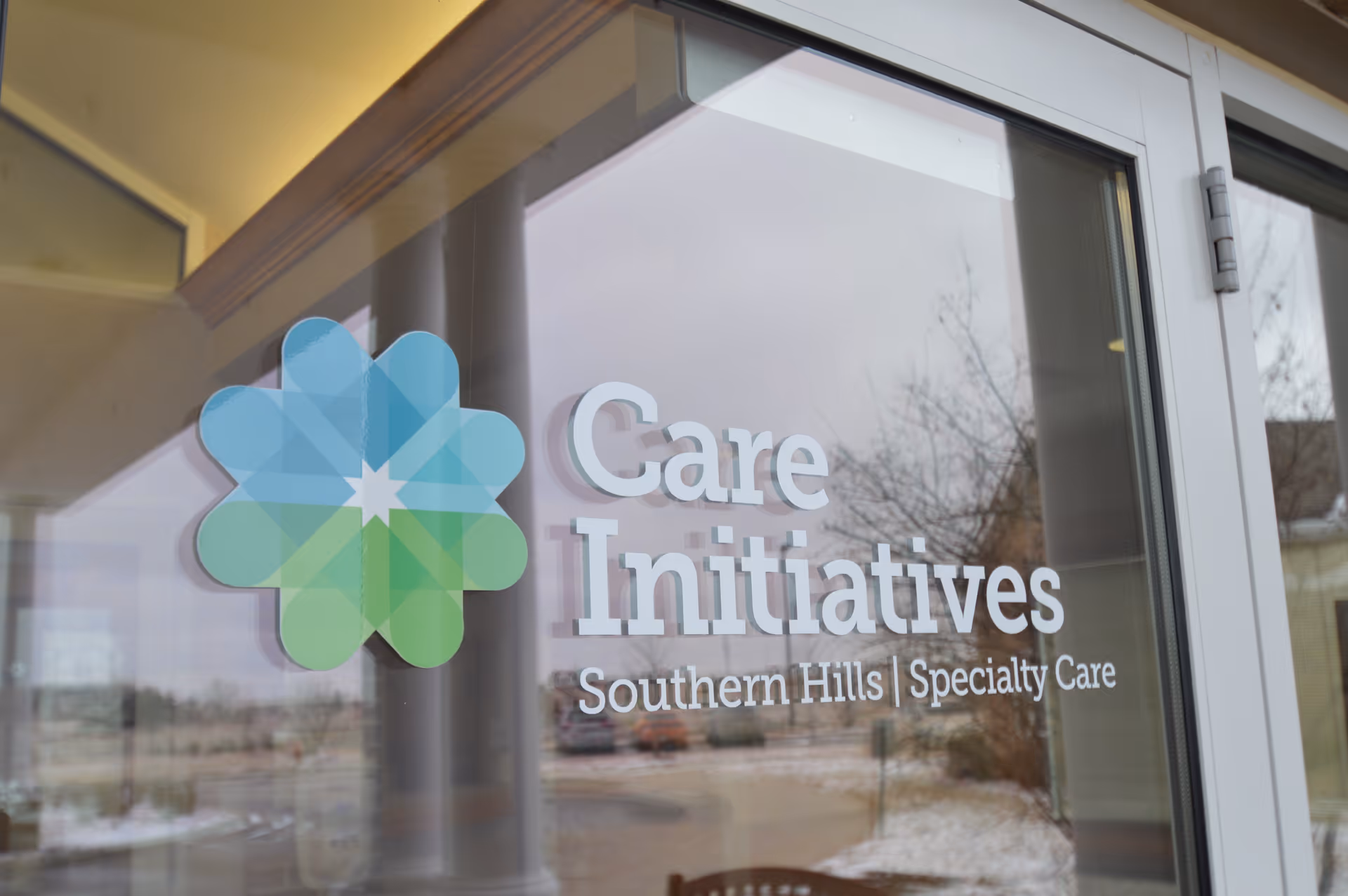 Glass entrance door displaying a green-blue flower logo and the words 'Care Initiatives Southern Hills | Specialty Care'.