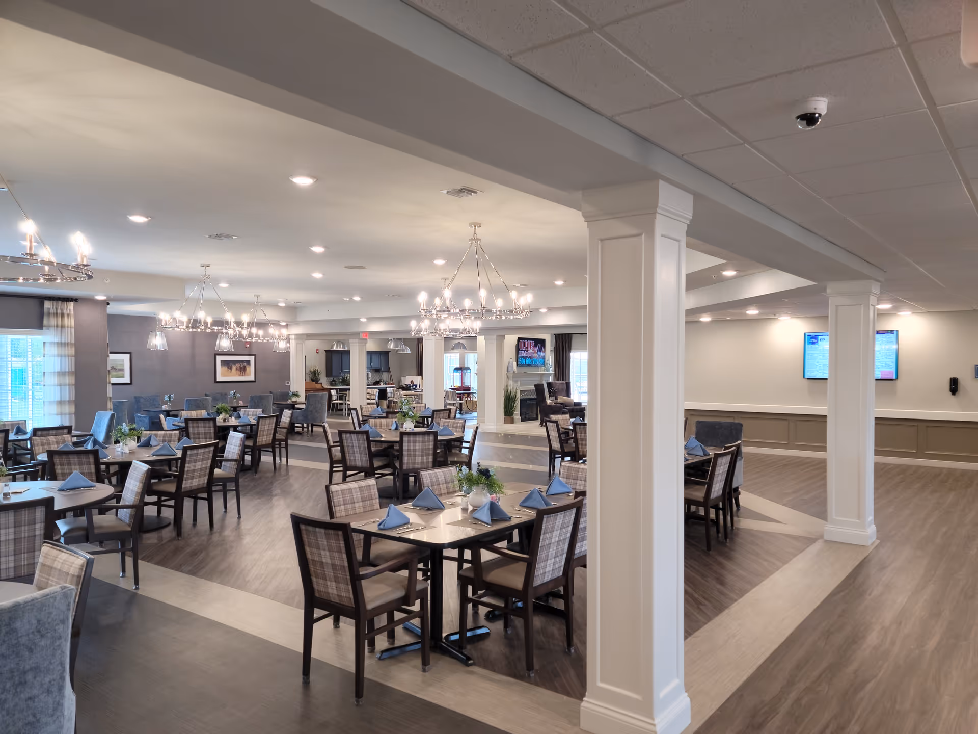 Spacious dining room in a senior living facility with many tables set for meals.