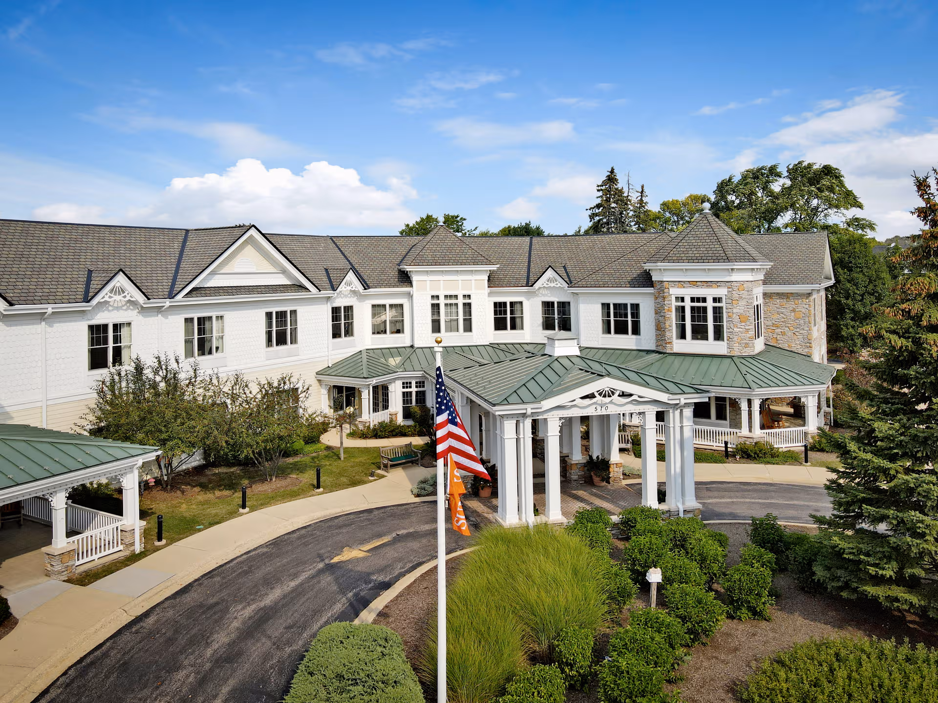 Exterior view of a senior living facility with a covered entrance and manicured landscaping.