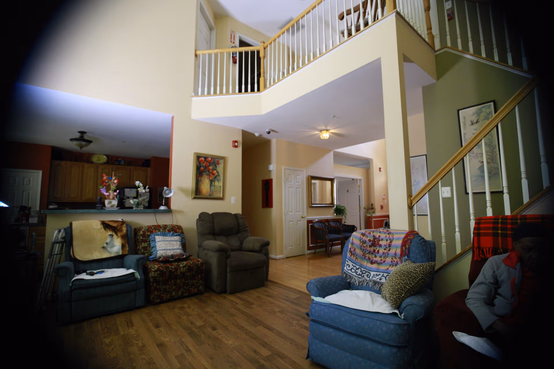 Open living area of a senior residence with couches, stairs, and a kitchen nook.