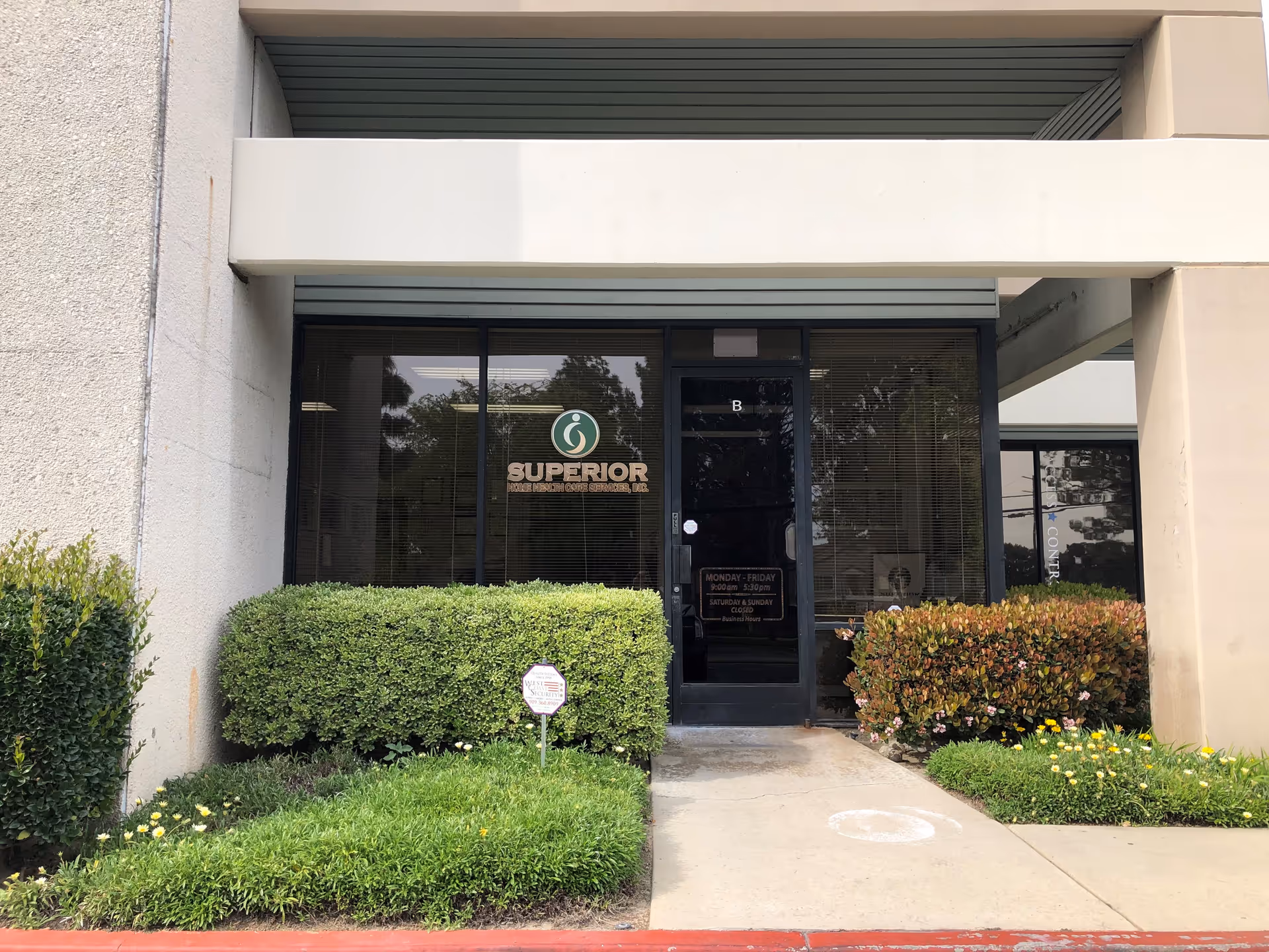 Front entrance of Superior Home Health Care with glass doors and trimmed shrubs.