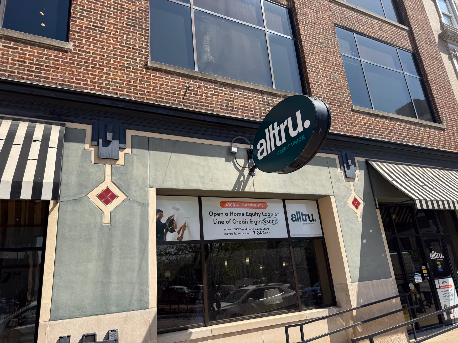 Brick storefront with striped awnings and a round altru credit union sign.