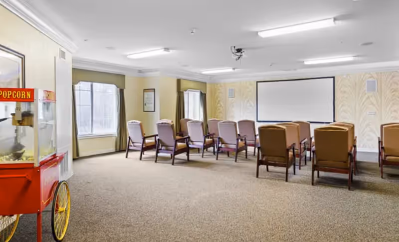 Interior of a senior living facility with rows of chairs facing a projector screen.