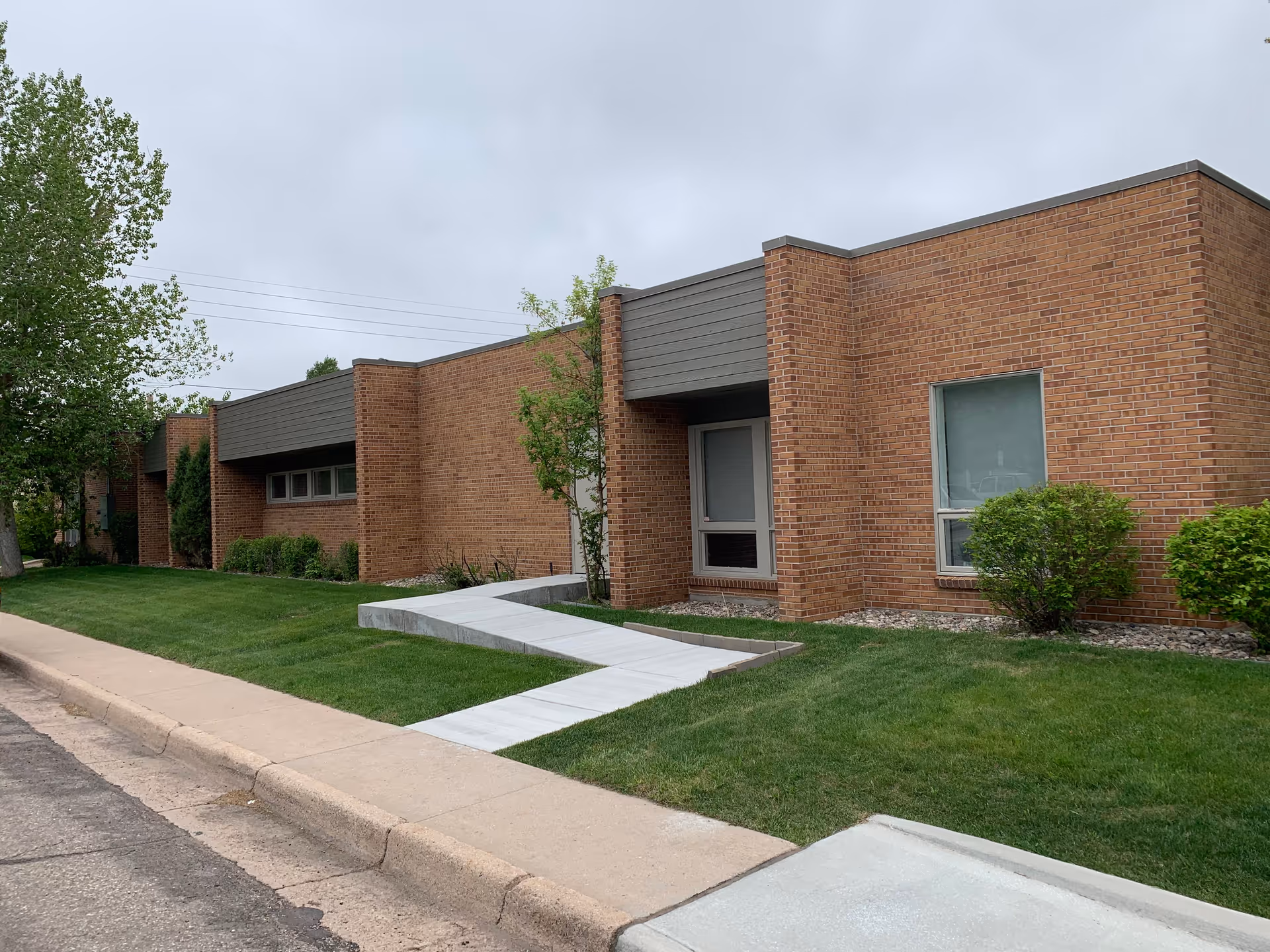 Brick facility exterior with a ramp, sidewalk, and manicured lawn along the building.
