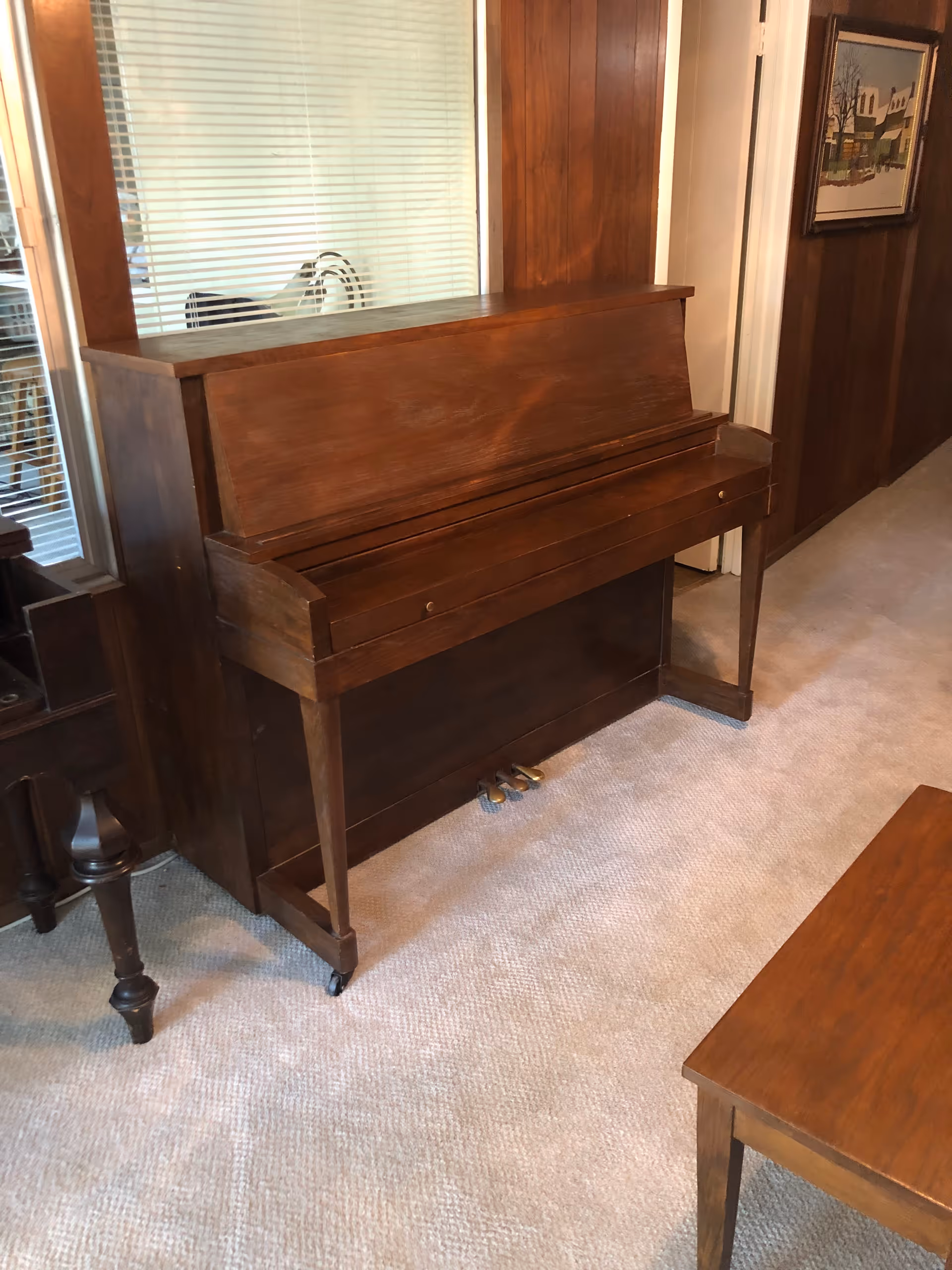 Dark wooden upright piano beside paneled wall in a senior living room.