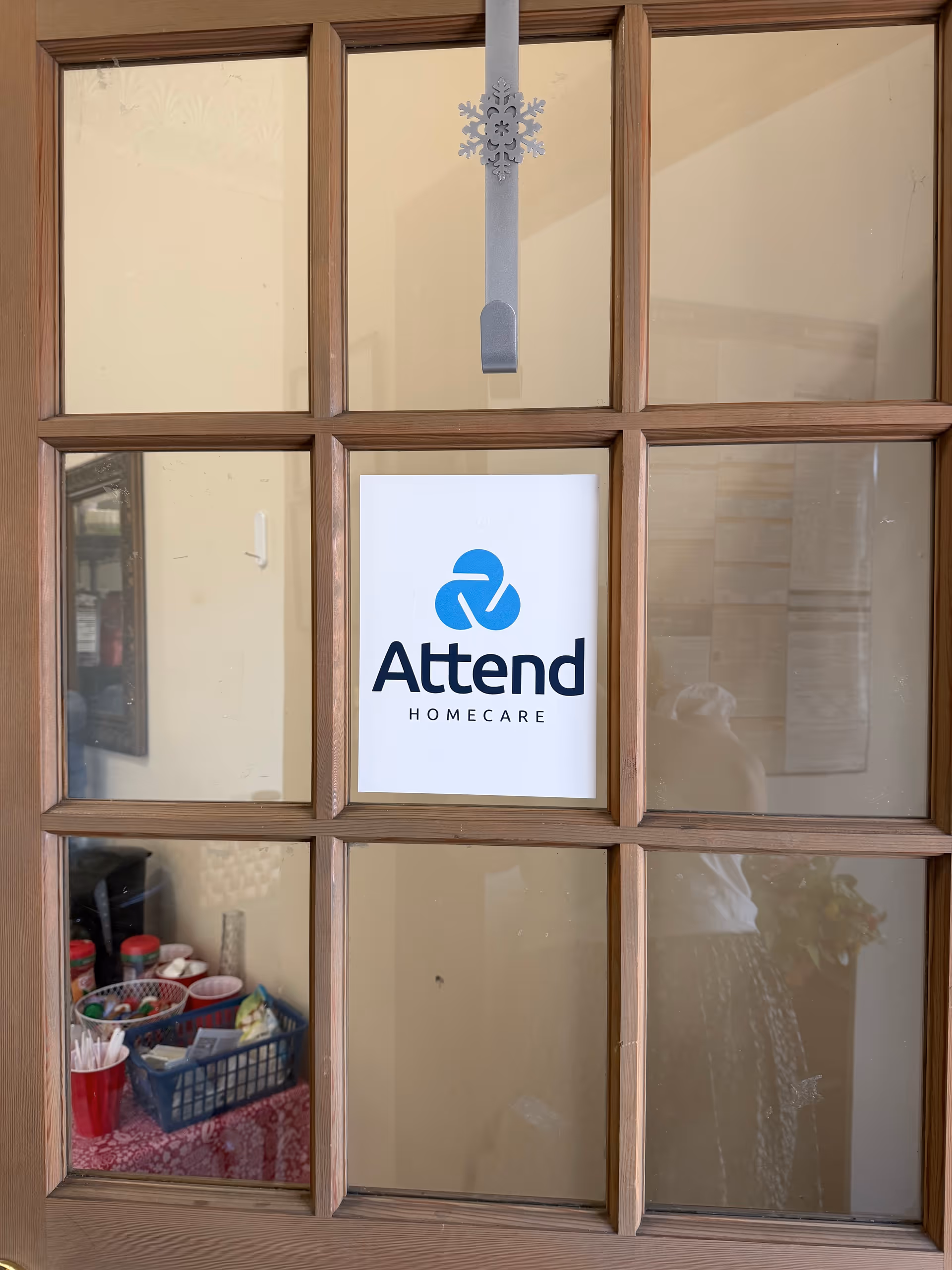 Wood-framed glass door displaying Attend Homecare sign inside a tidy interior lobby.